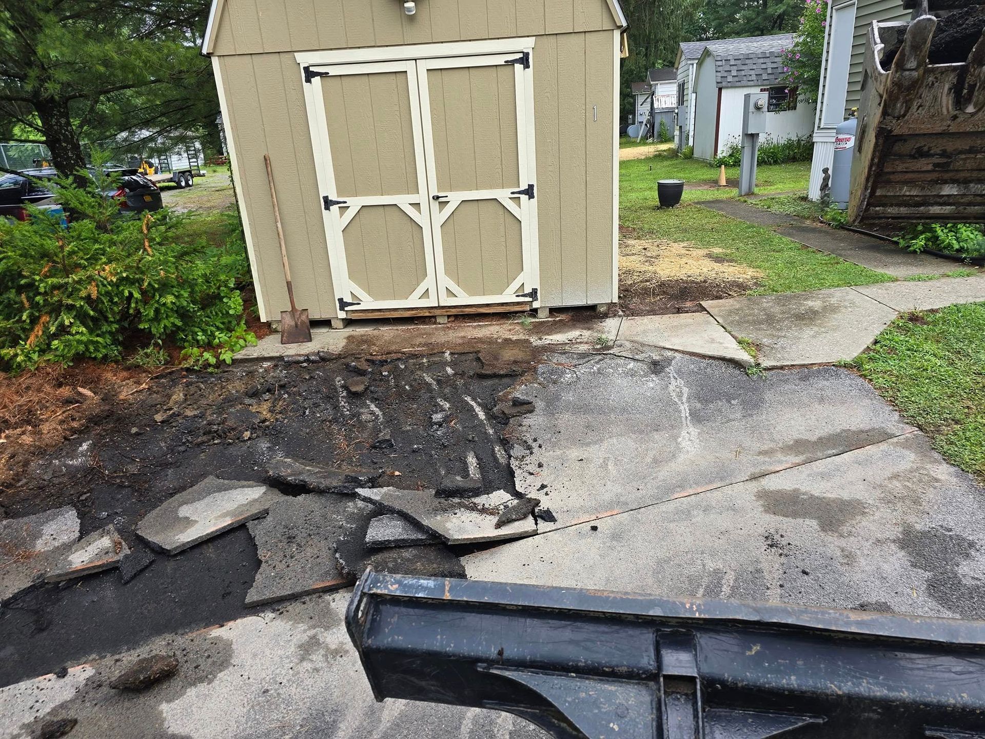 A shed is sitting in the middle of a concrete driveway.