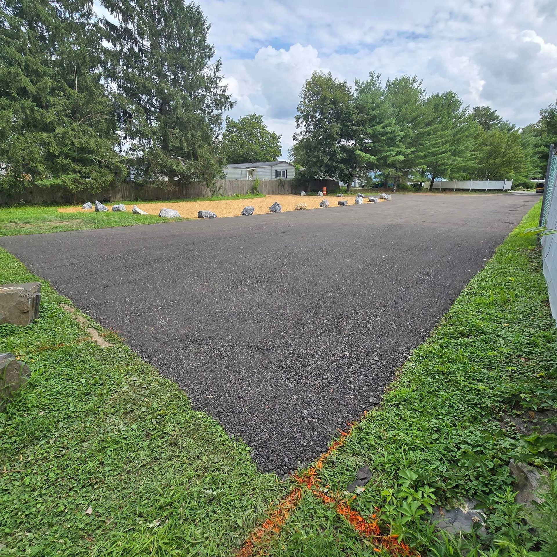A large empty parking lot surrounded by grass and trees
