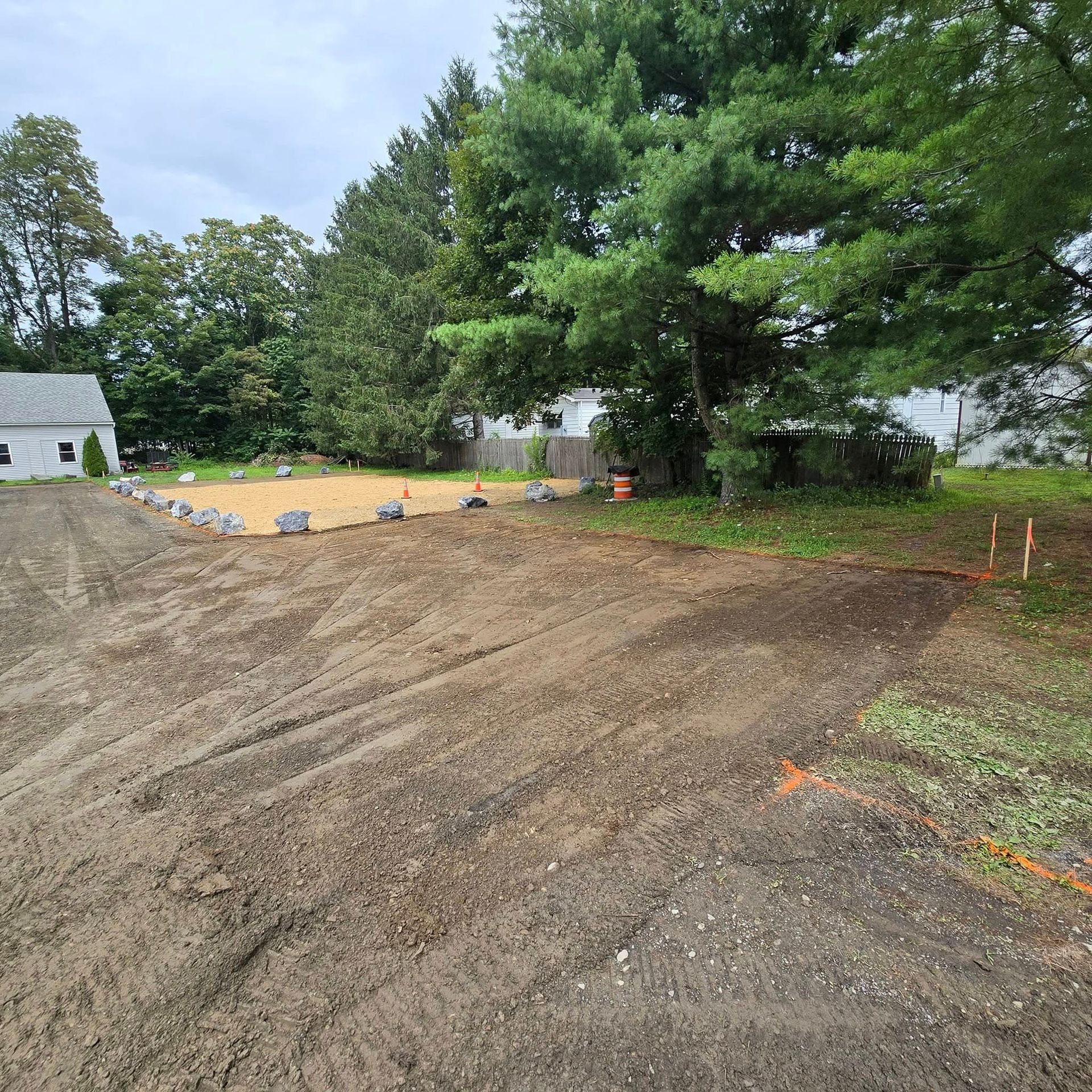 A dirt road leading to a house with trees in the background.