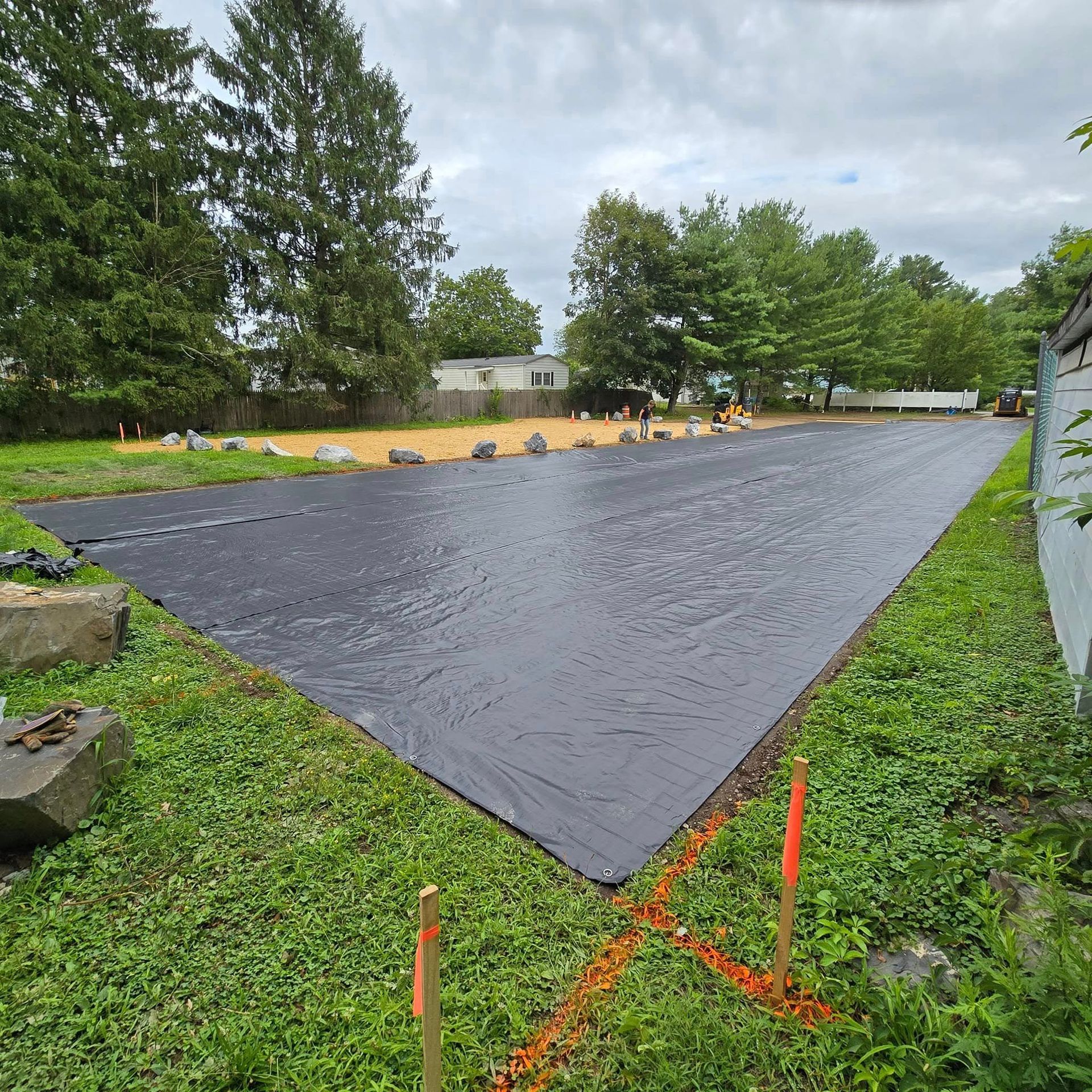 A large black tarp is sitting on top of a lush green field.