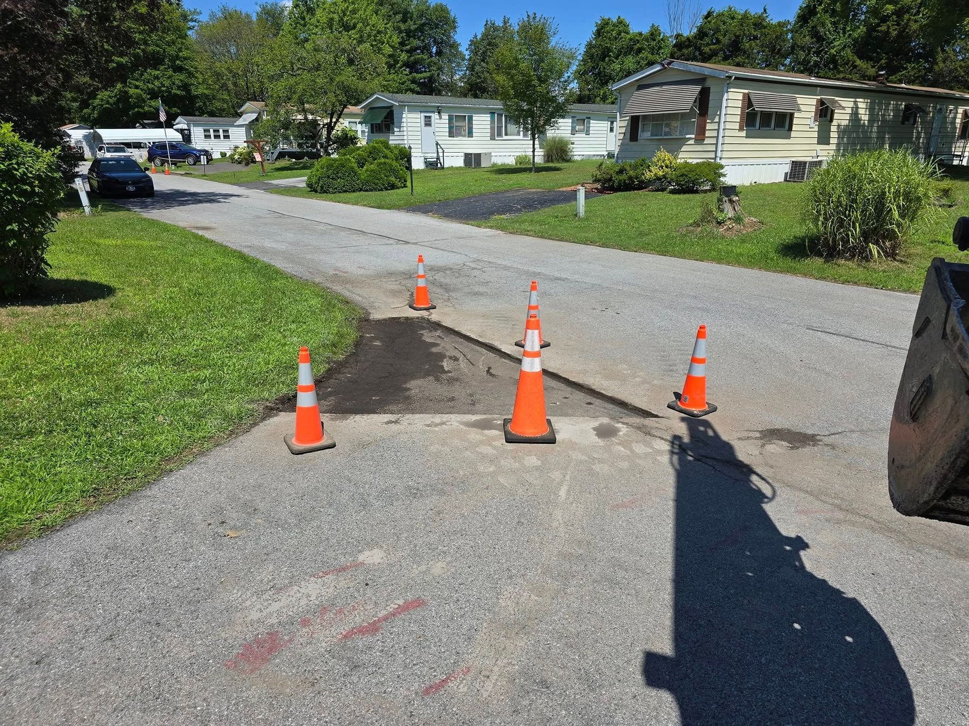 Three orange and white traffic cones are on the side of a road.