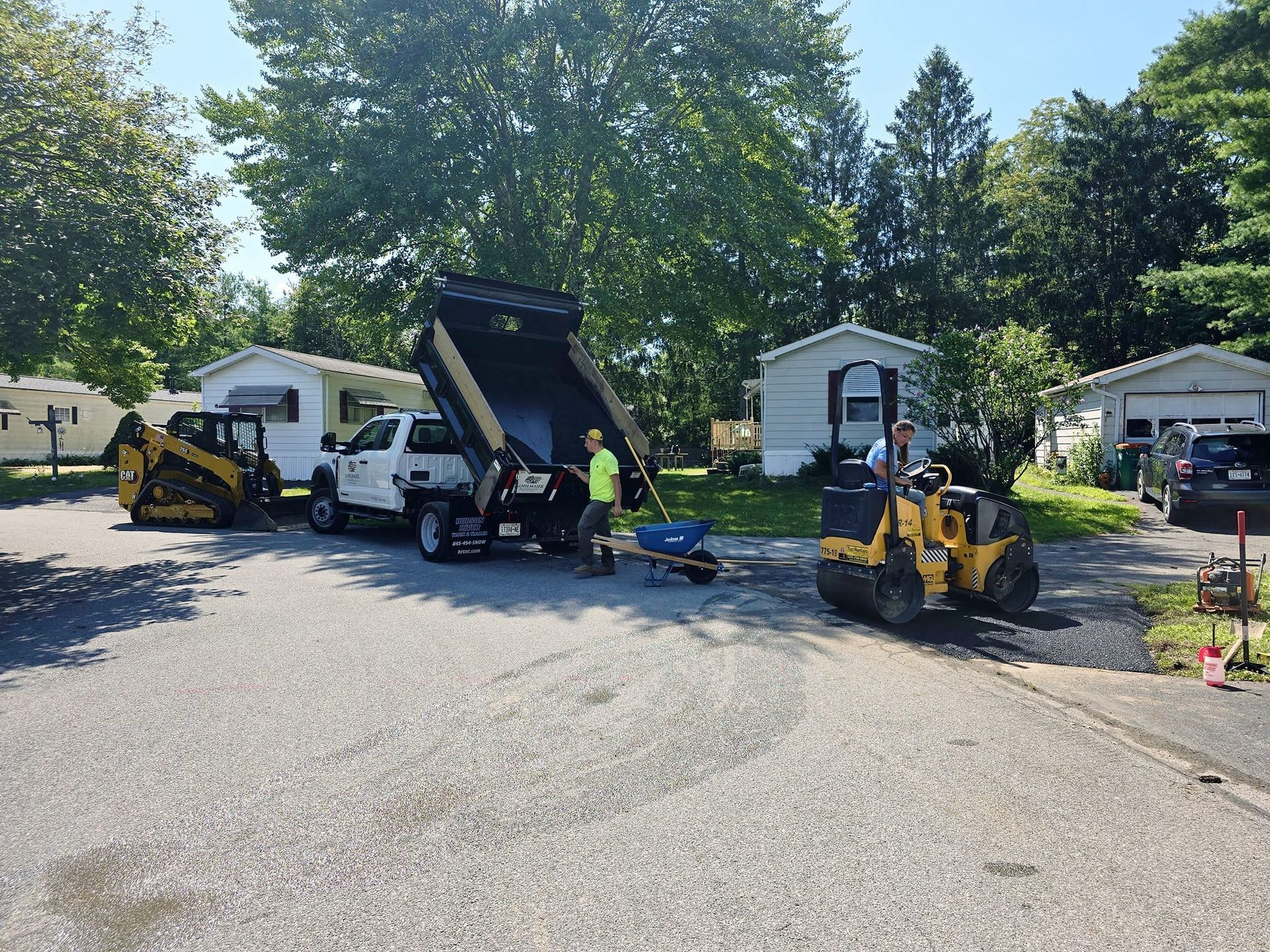 A group of construction vehicles are parked in a driveway.