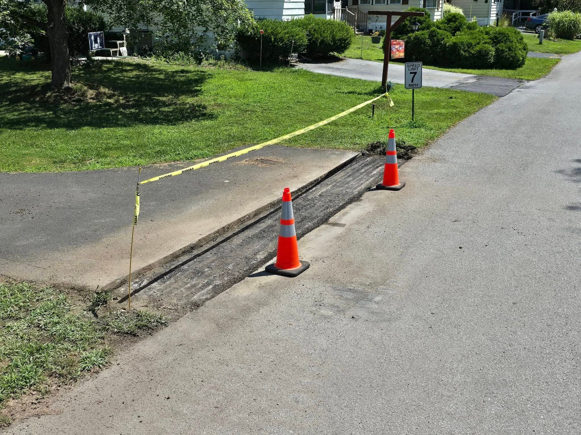 Two orange traffic cones are on the side of a road