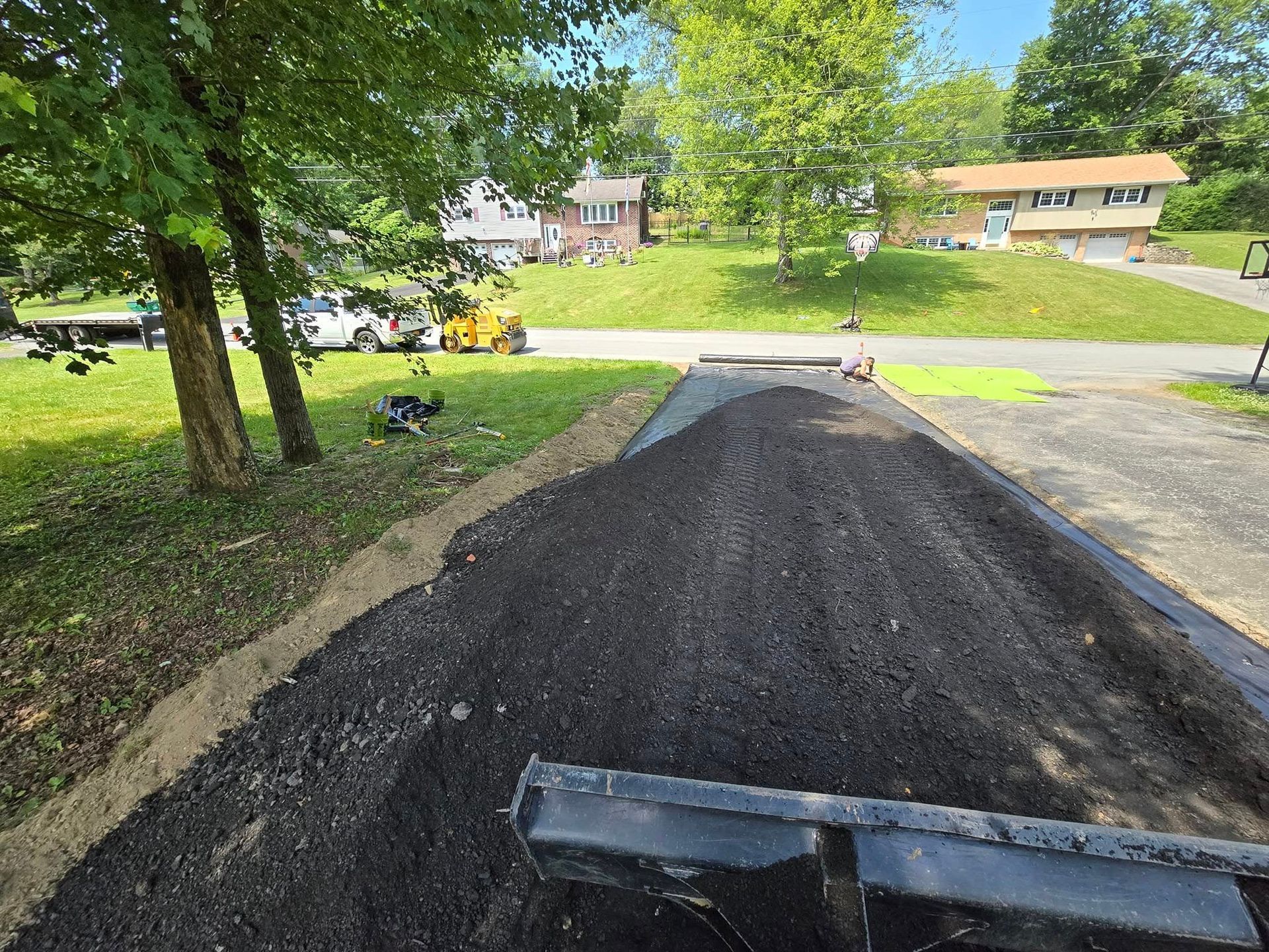 A pile of dirt is sitting on the side of a road next to a house.