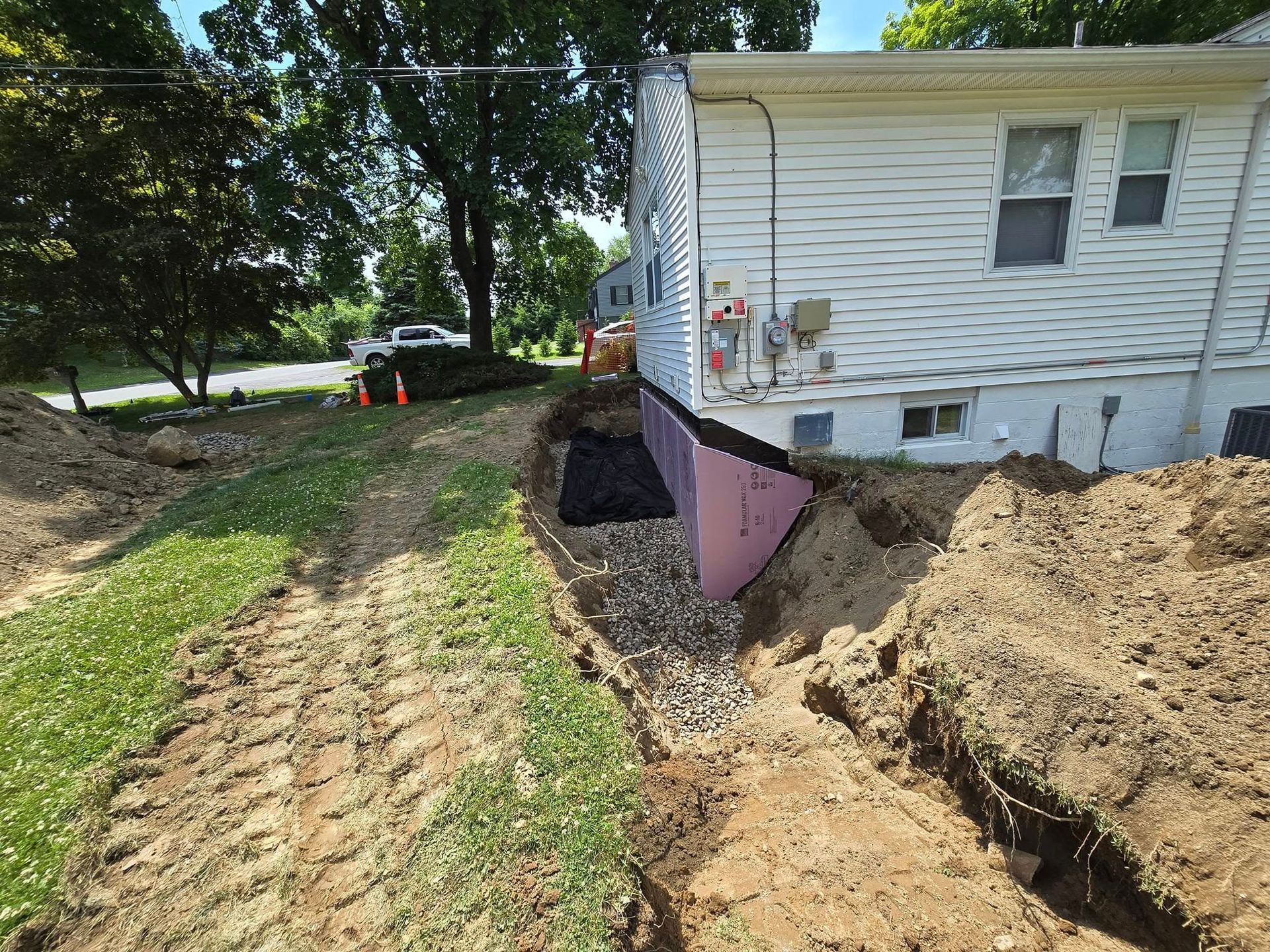 A white house is being remodeled and a large pile of dirt is in front of it.