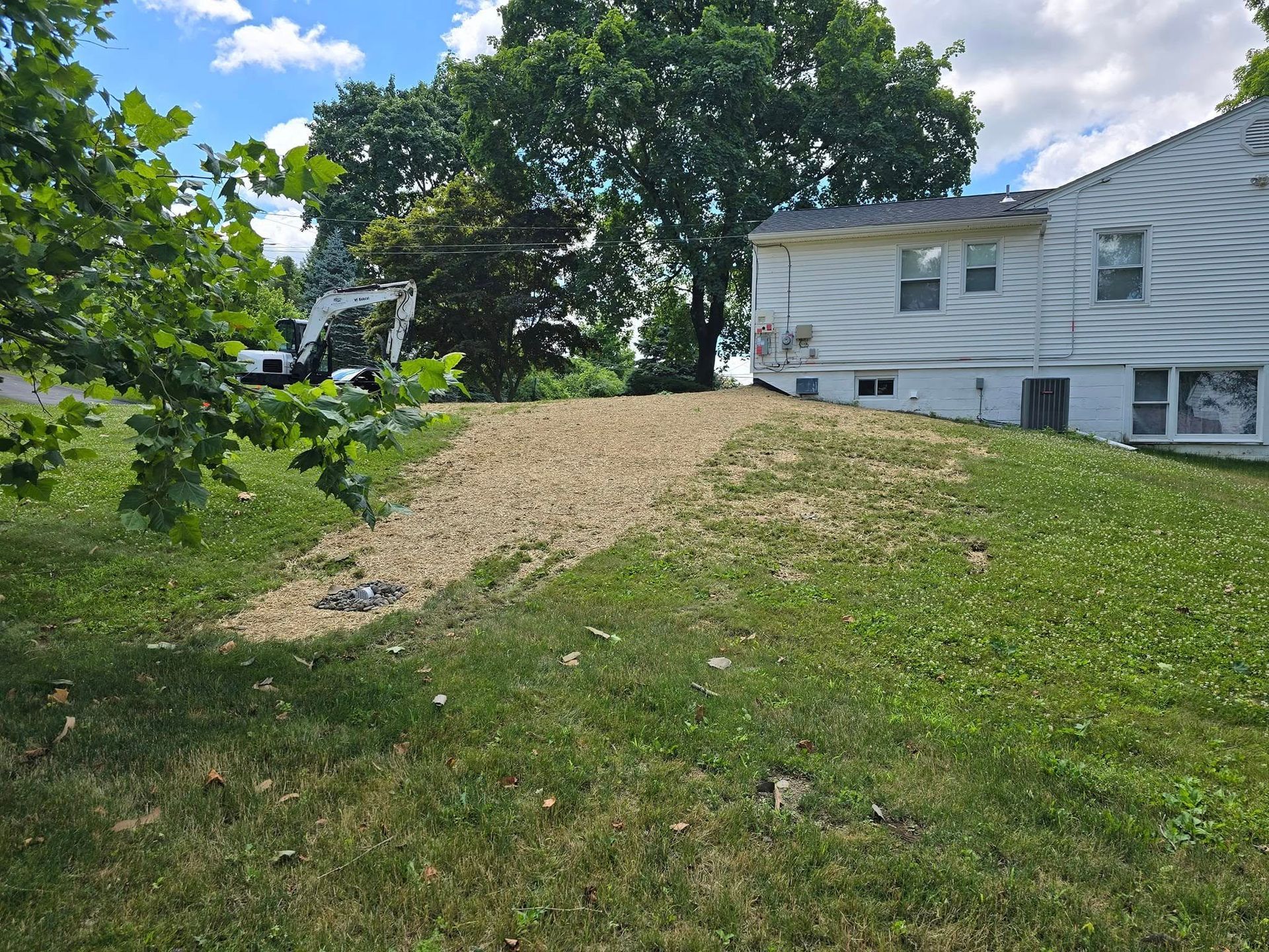 A large white house is sitting on top of a lush green hill.