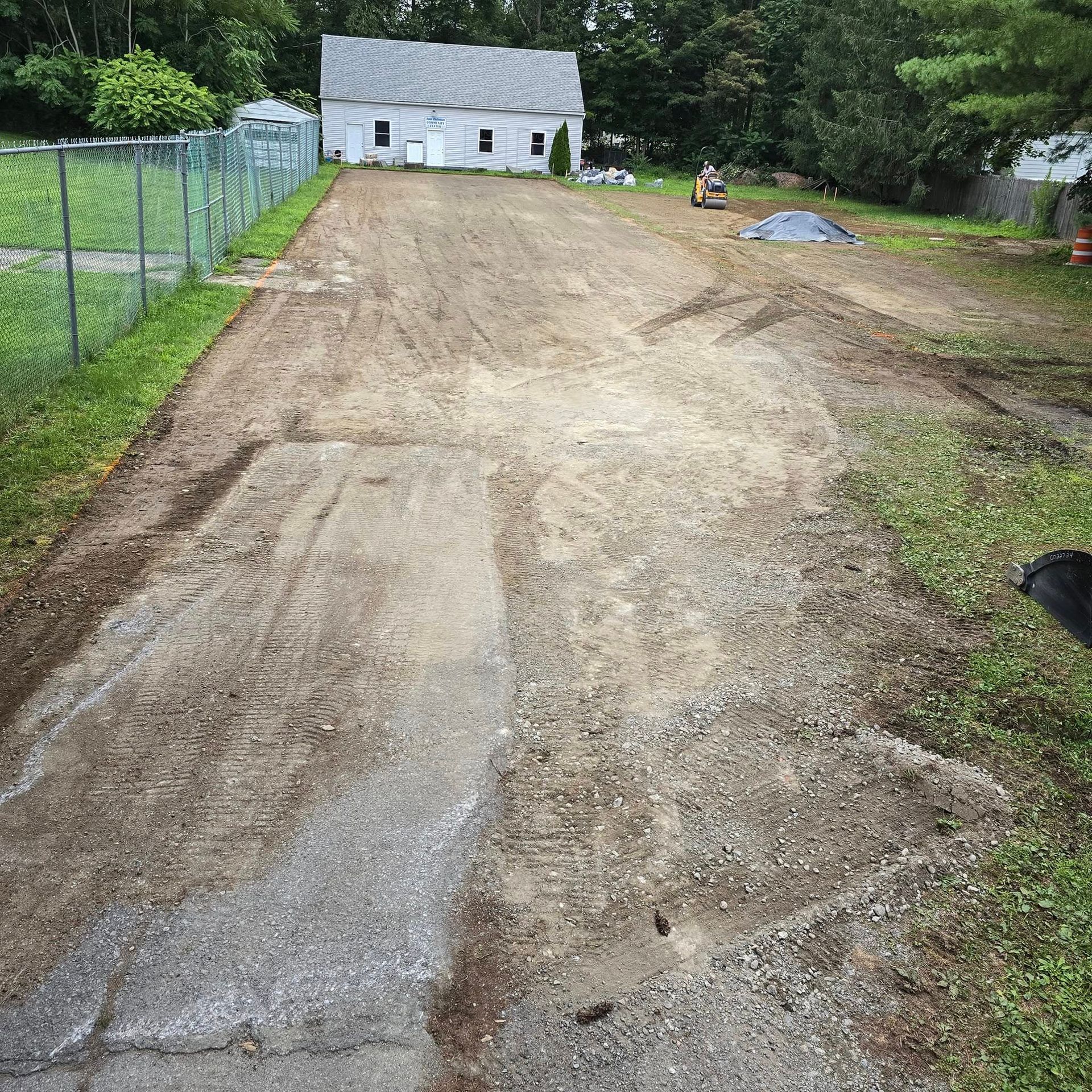 A dirt road leading to a house with a chain link fence.