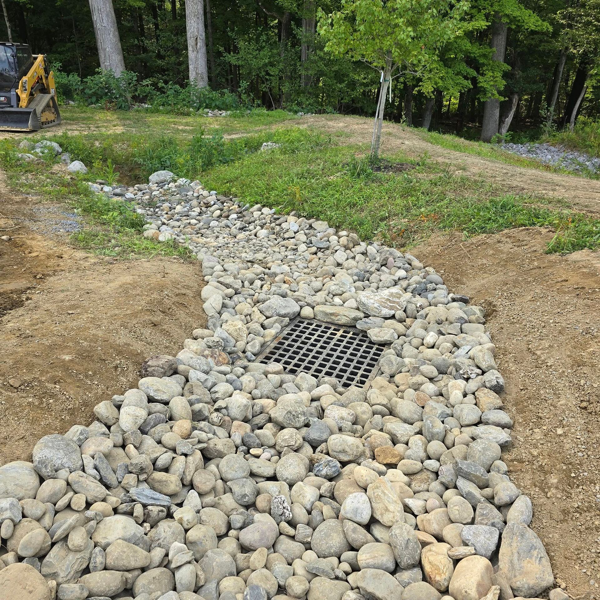 A stream of rocks with a drain in the middle of it.