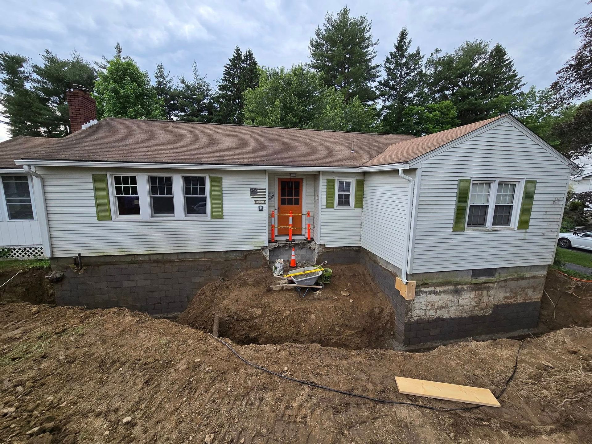 A house with a hole in the ground in front of it.