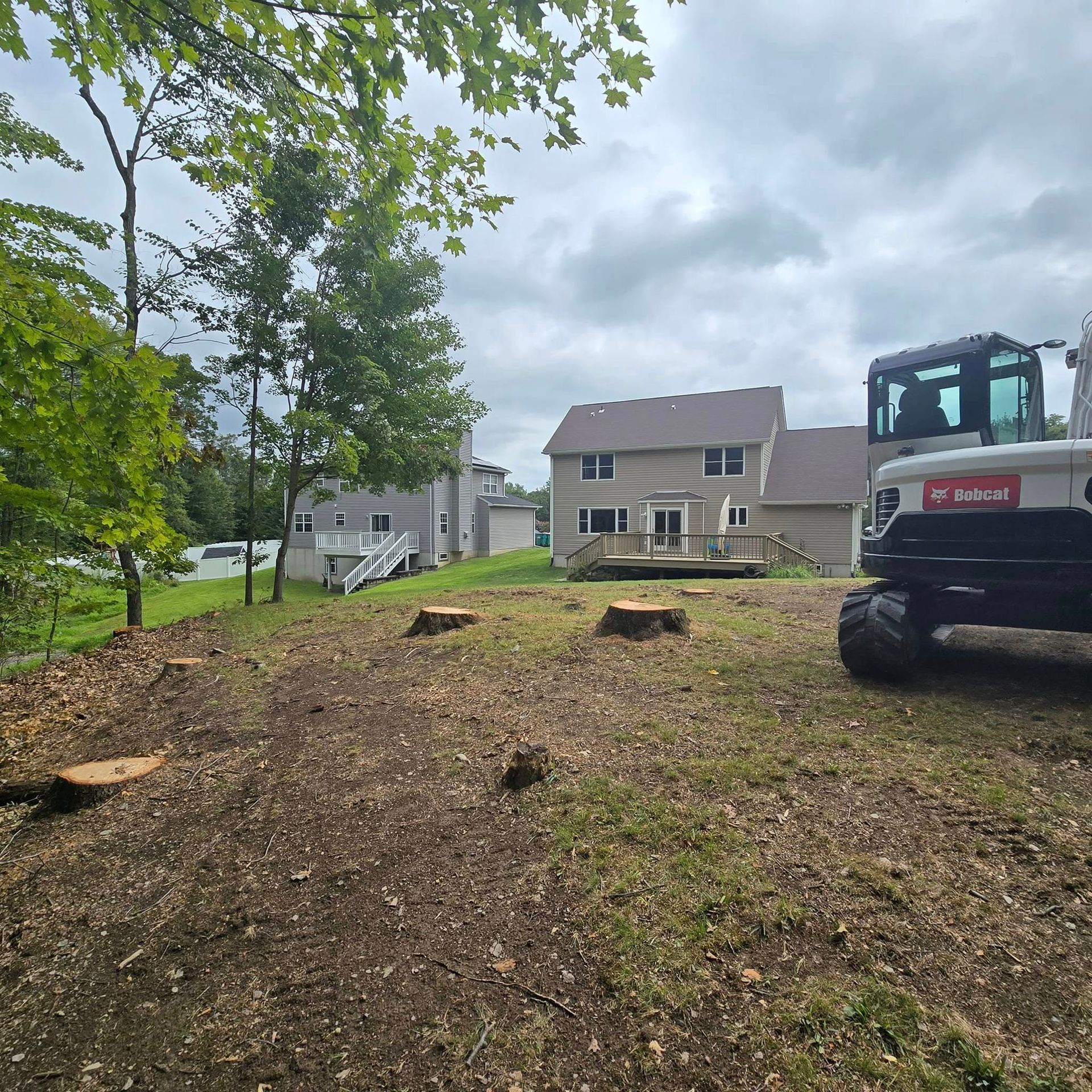 A large excavator is parked in a grassy field in front of a house.