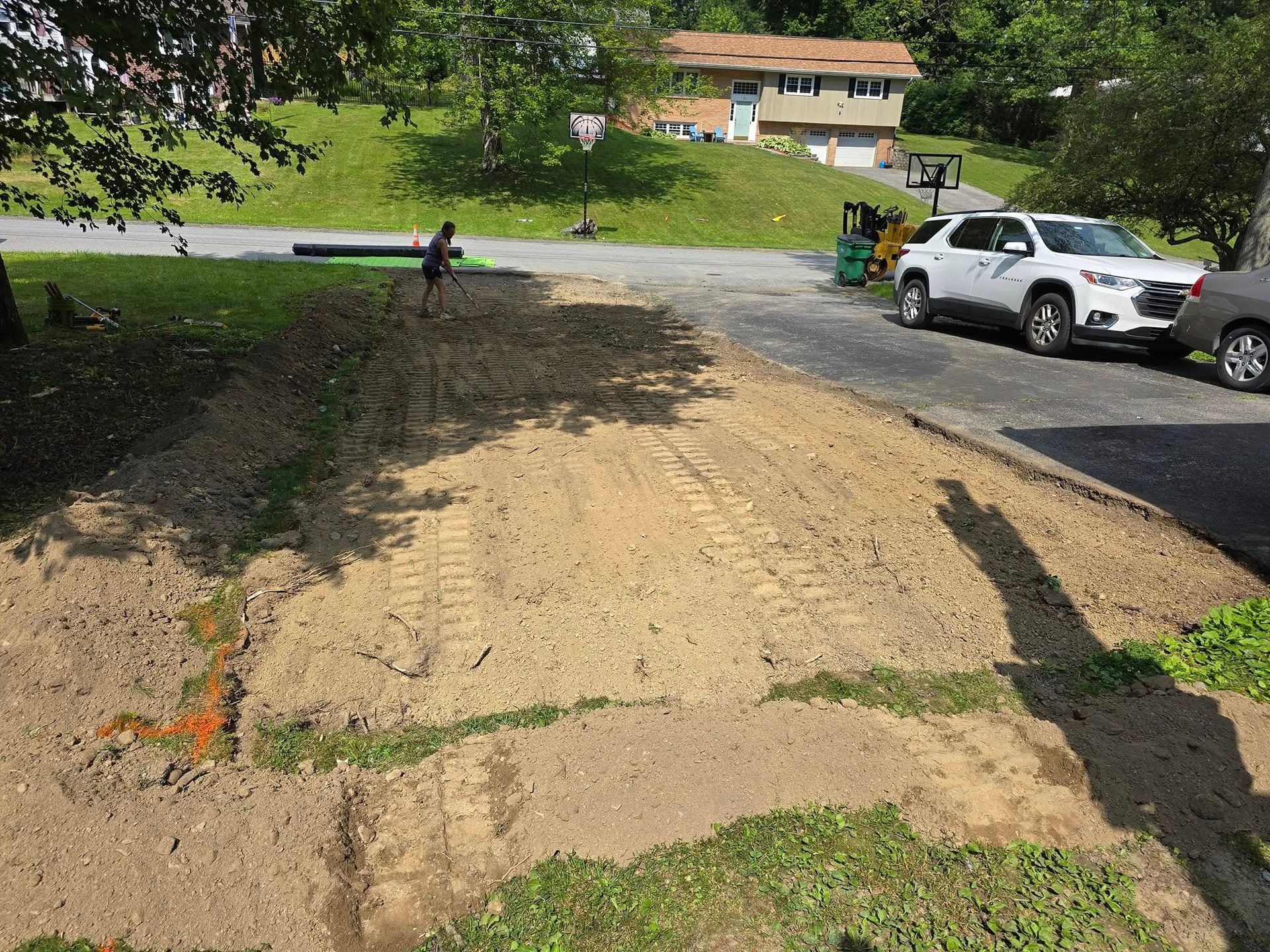 A white suv is parked on the side of a dirt road next to a house.