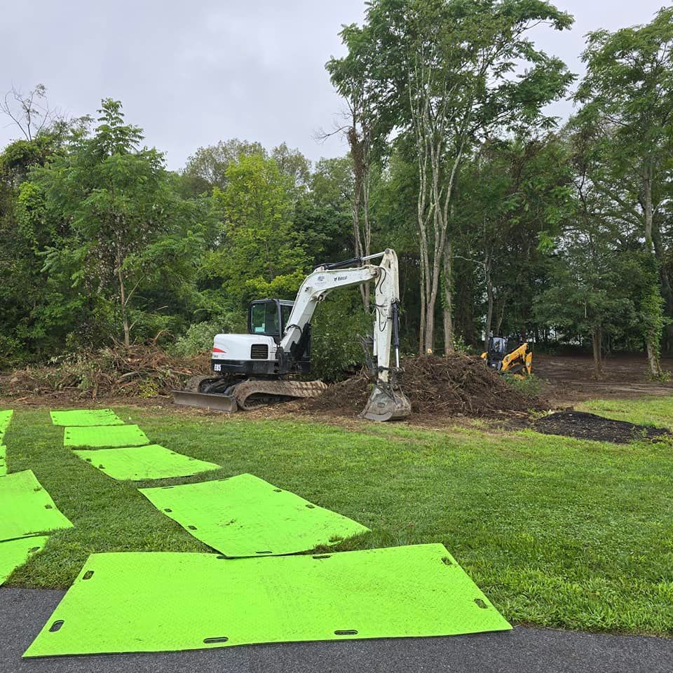 A white excavator is digging a hole in a grassy field.