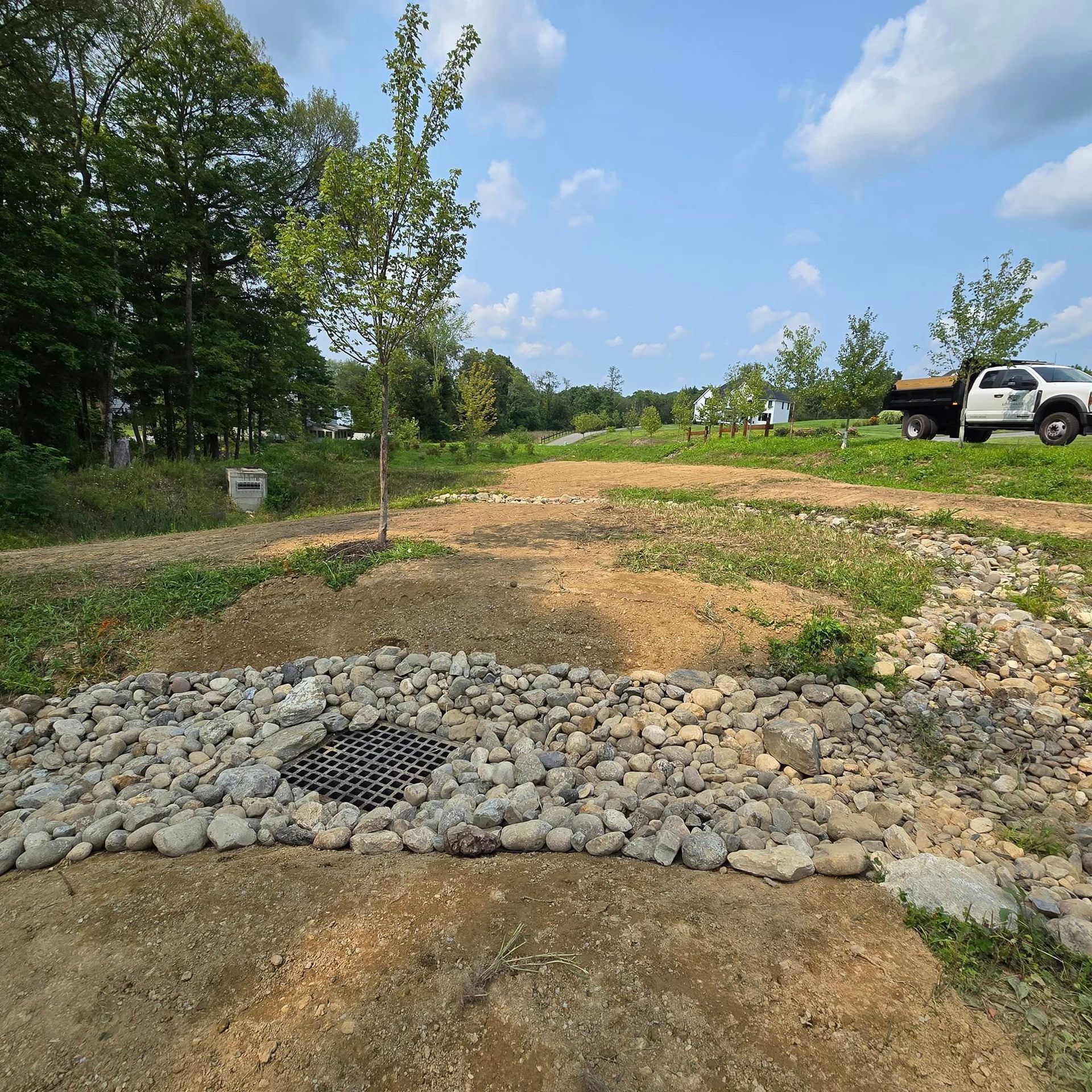 A white truck is parked on the side of a dirt road