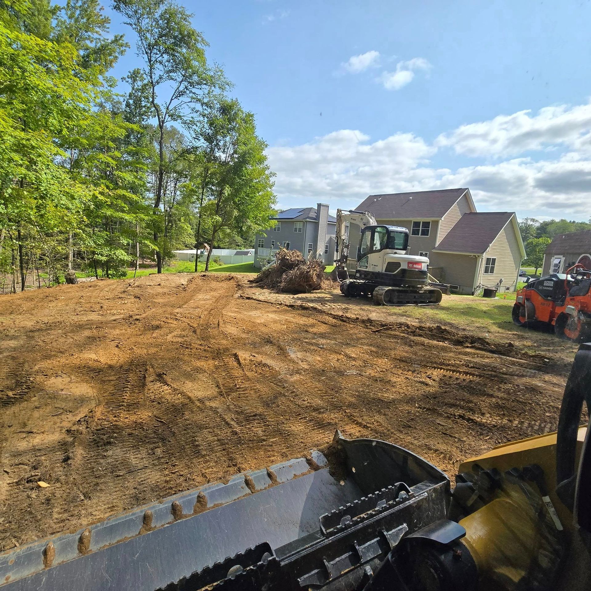 A bulldozer is working on a dirt field in front of a house.