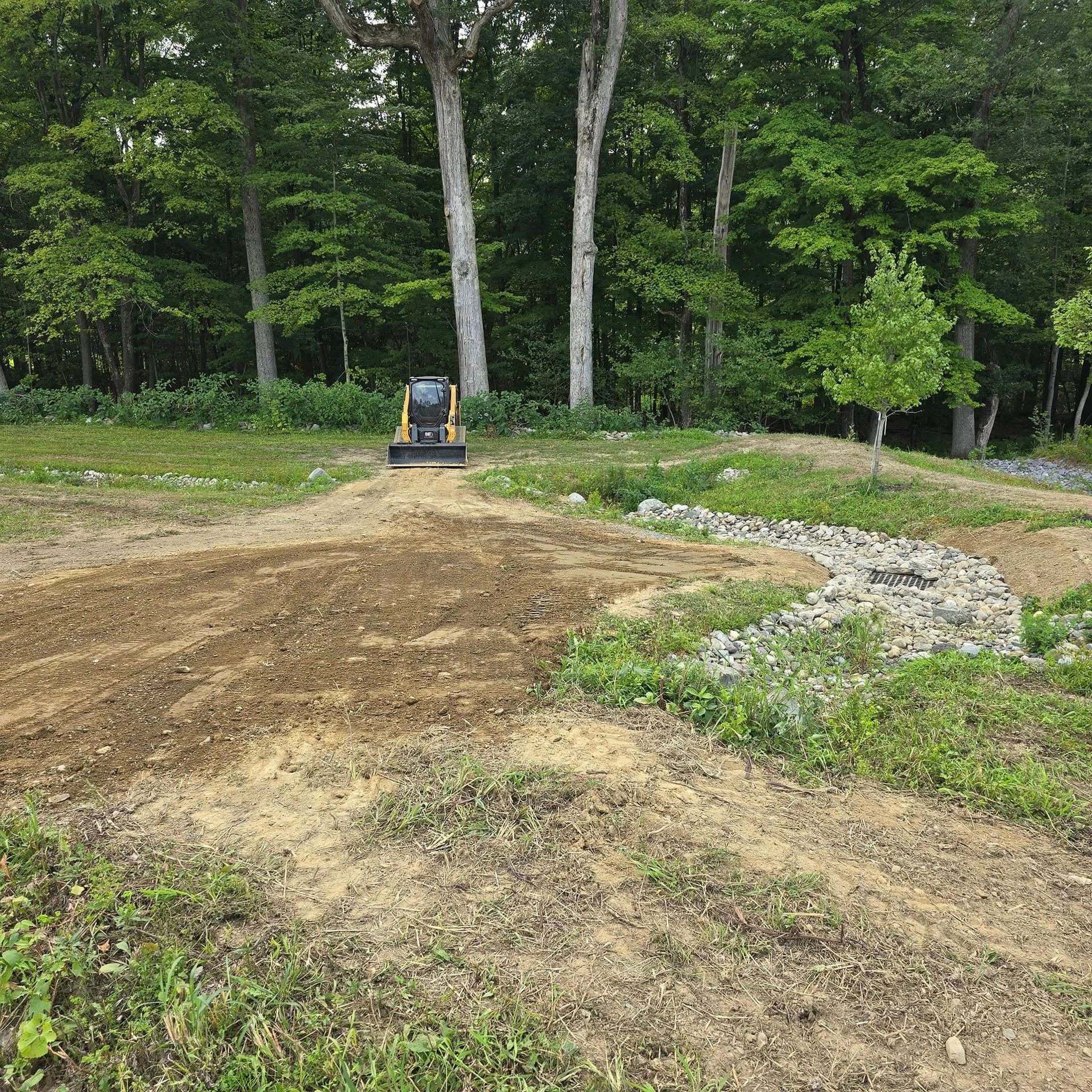 A bulldozer is moving dirt in a field with trees in the background.