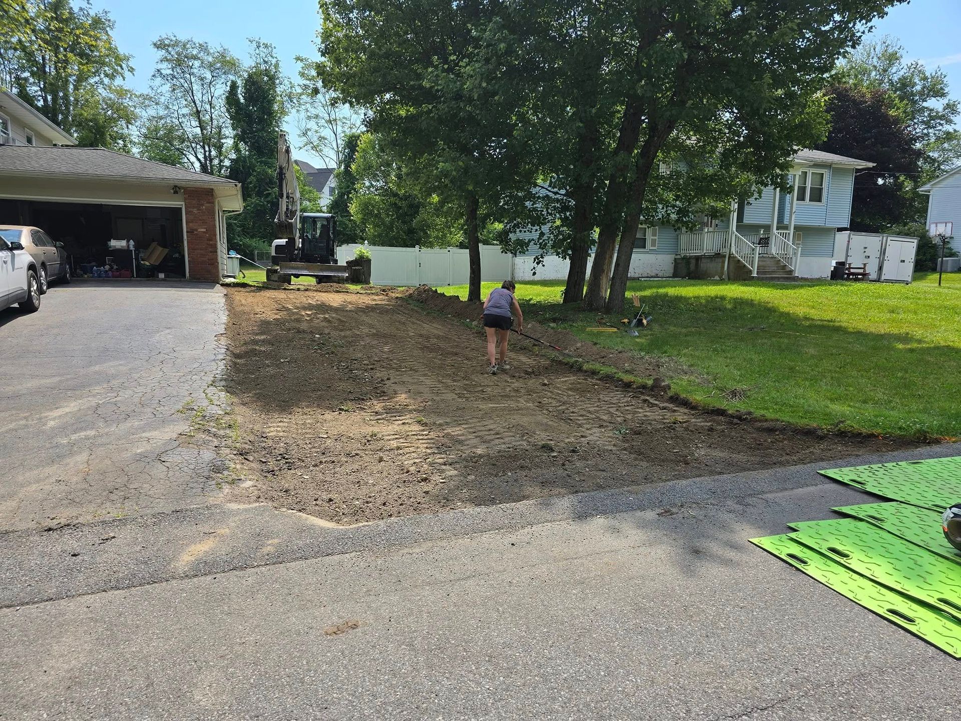 A person is walking down a dirt road in front of a house.