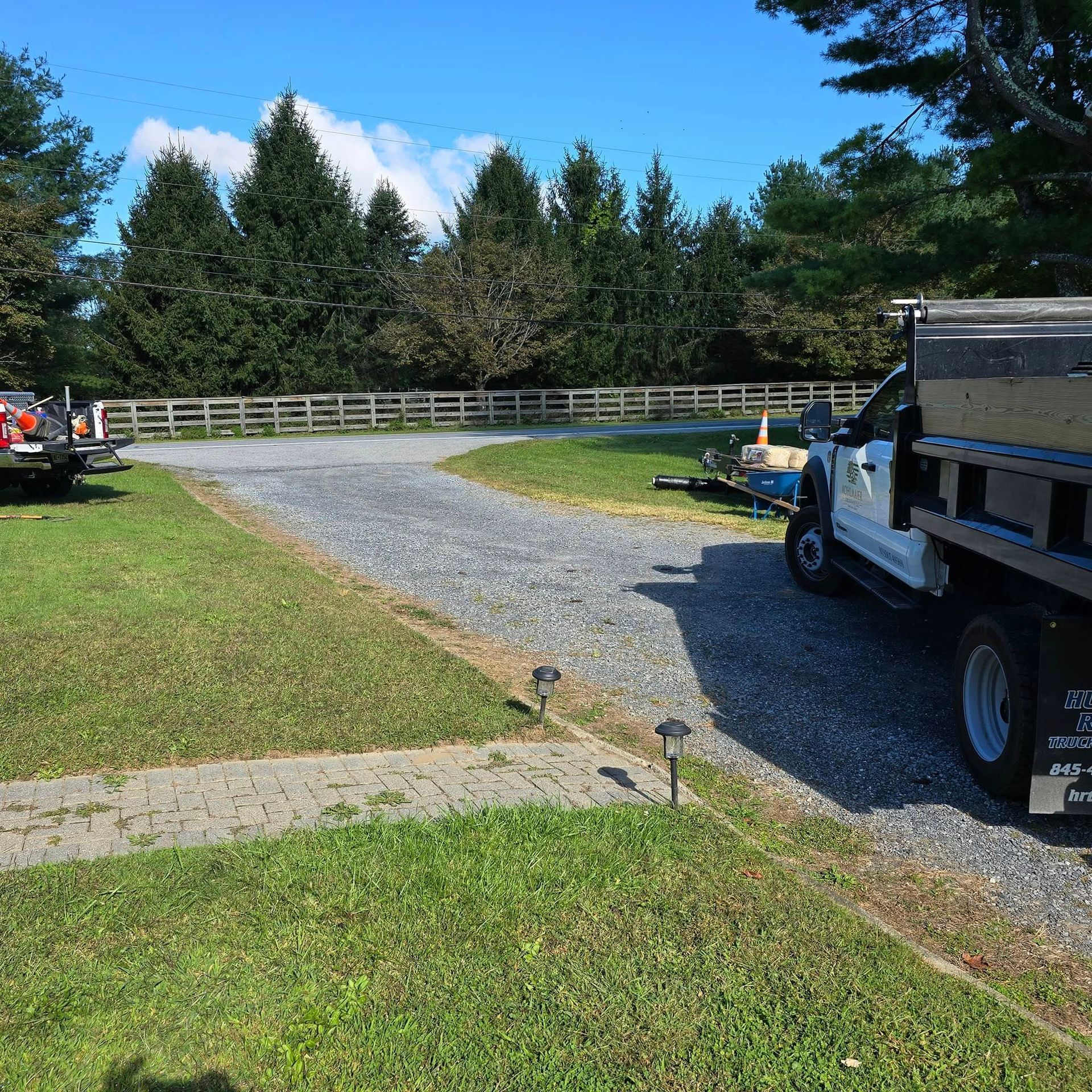 A dump truck is parked on the side of a gravel road.