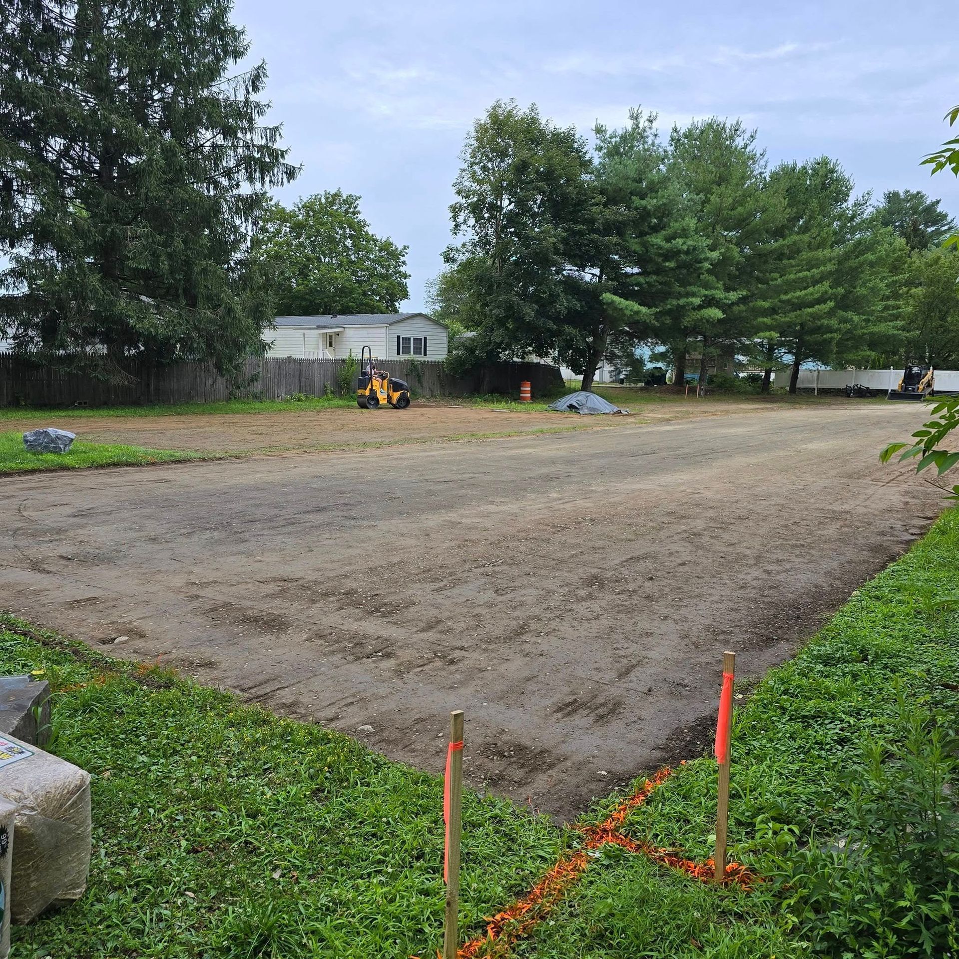 A large dirt field with trees and a house in the background.