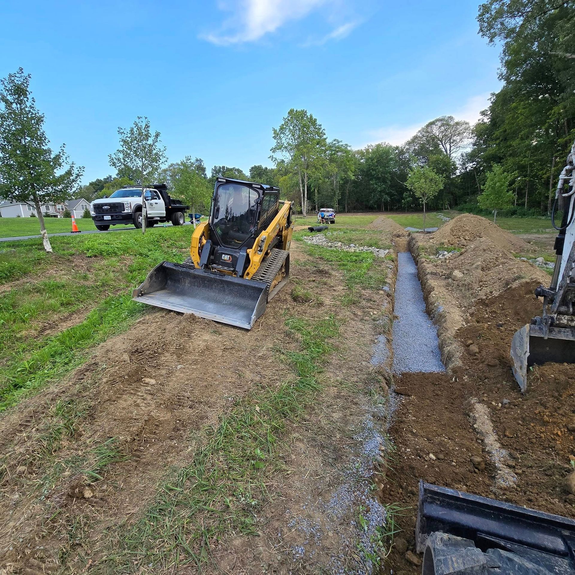 A bulldozer is driving down a dirt road next to a truck.