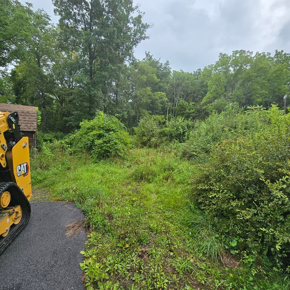 A yellow tractor is driving down a dirt road in a field.