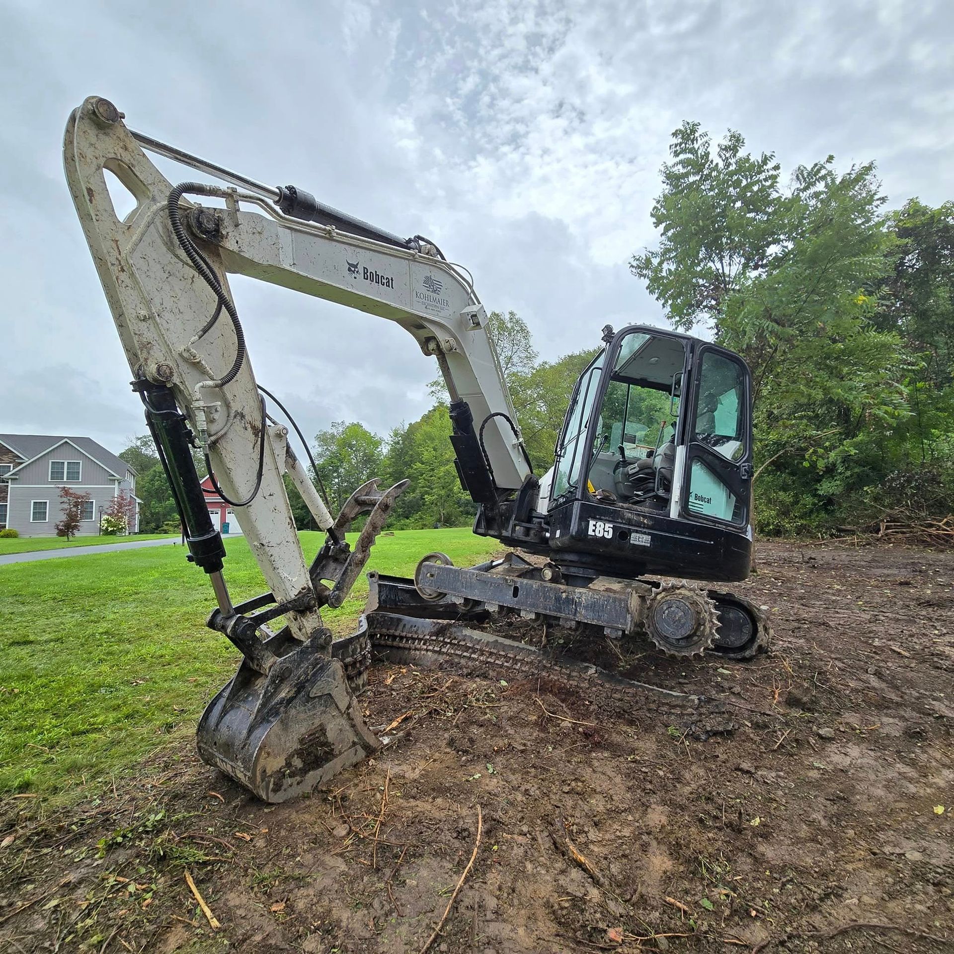 A white and black excavator is sitting on top of a dirt field.