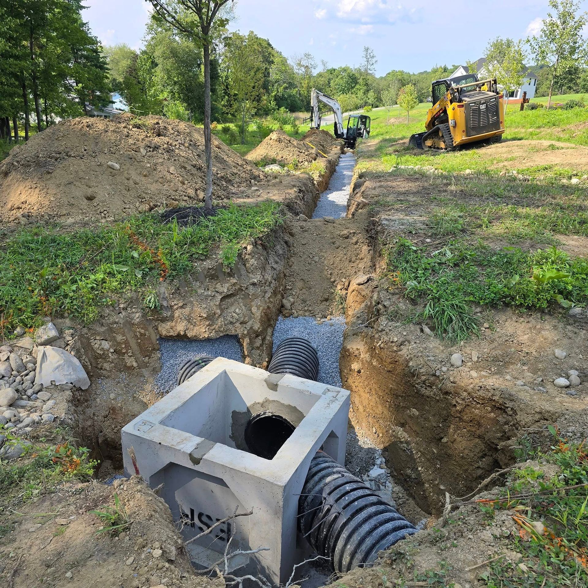 A drainage system is being installed in a field with a bulldozer in the background.