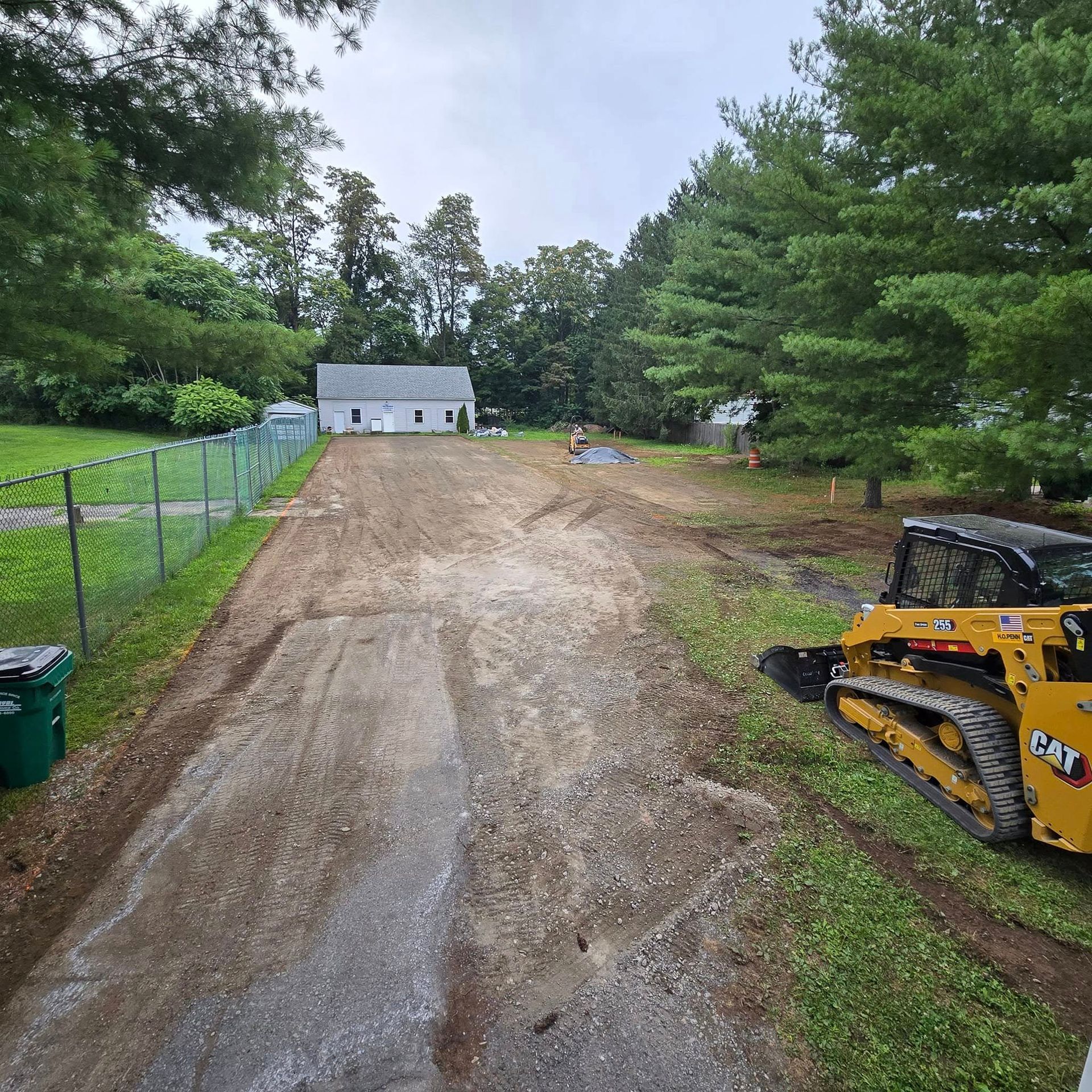 A yellow cat bulldozer is parked on the side of a dirt road.