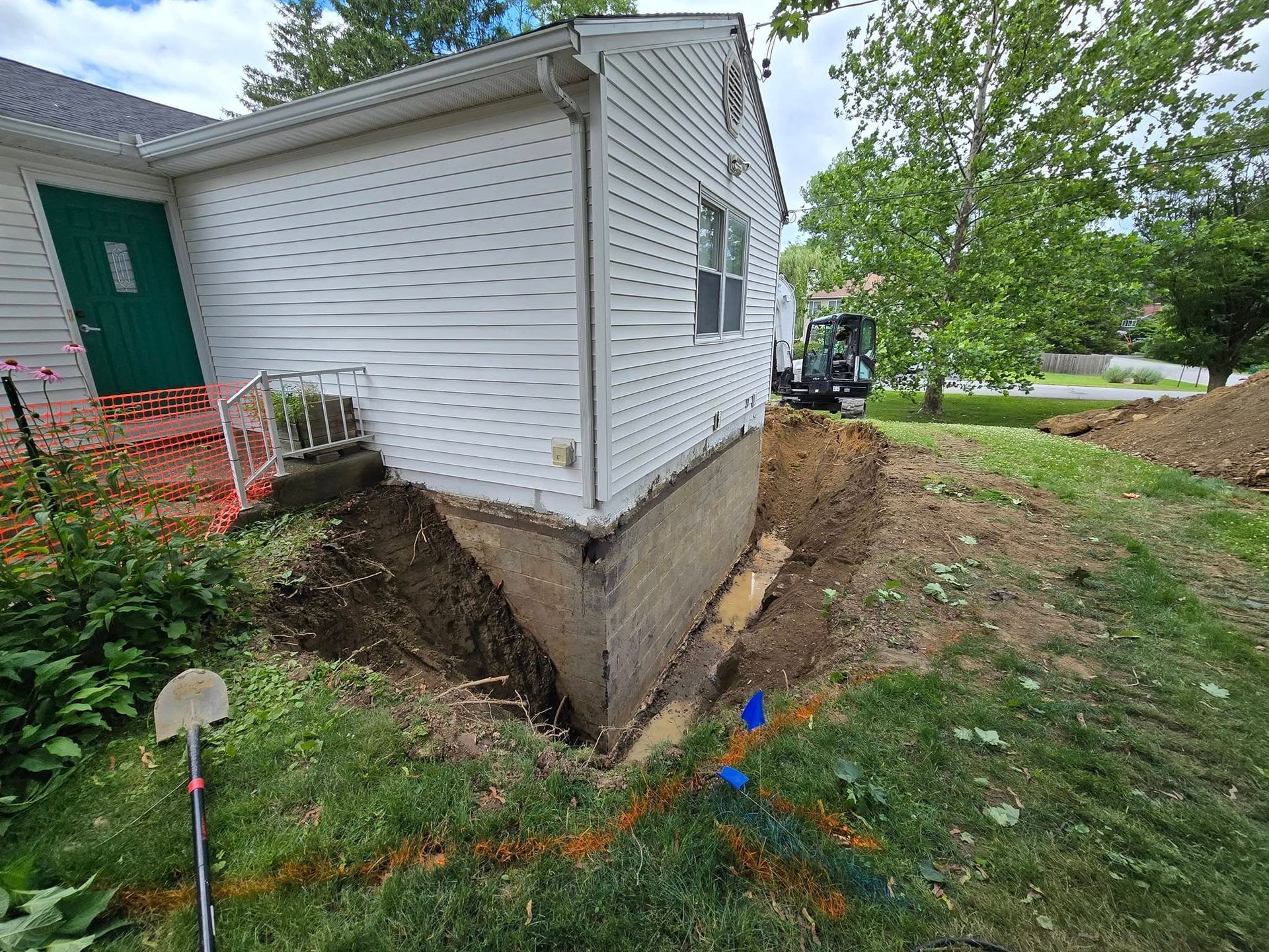 A white house with a green door is being remodeled.