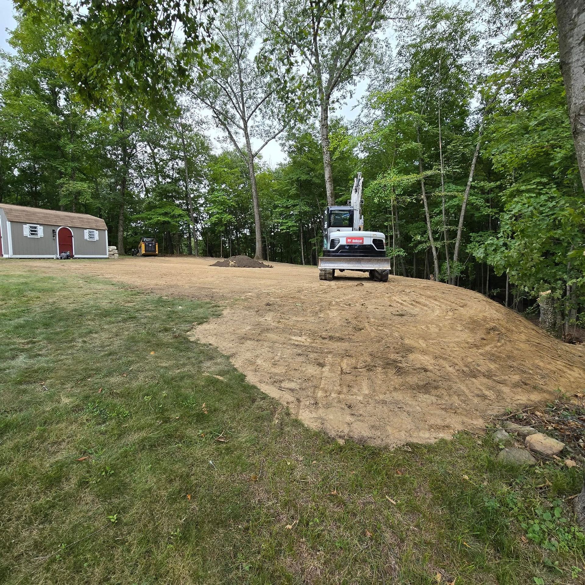 A bulldozer is moving dirt in a yard next to a house.