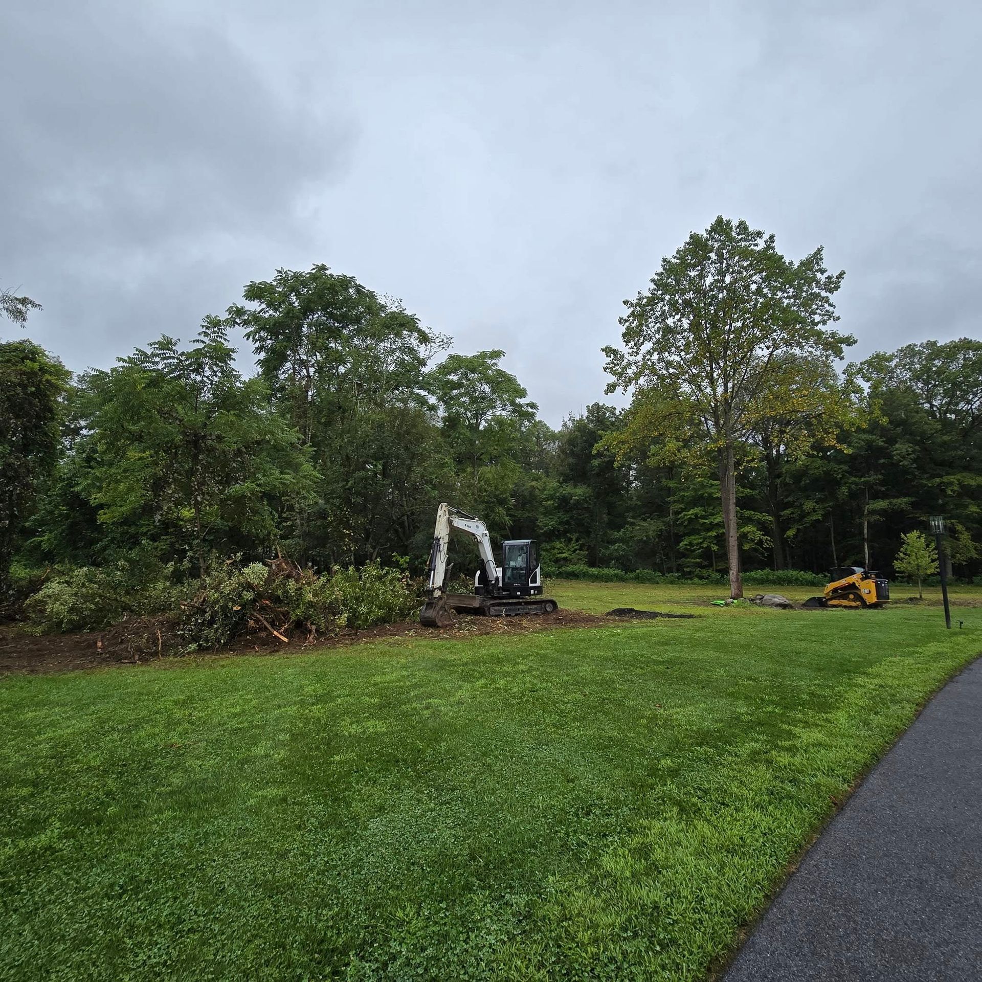 An excavator is sitting in the middle of a grassy field