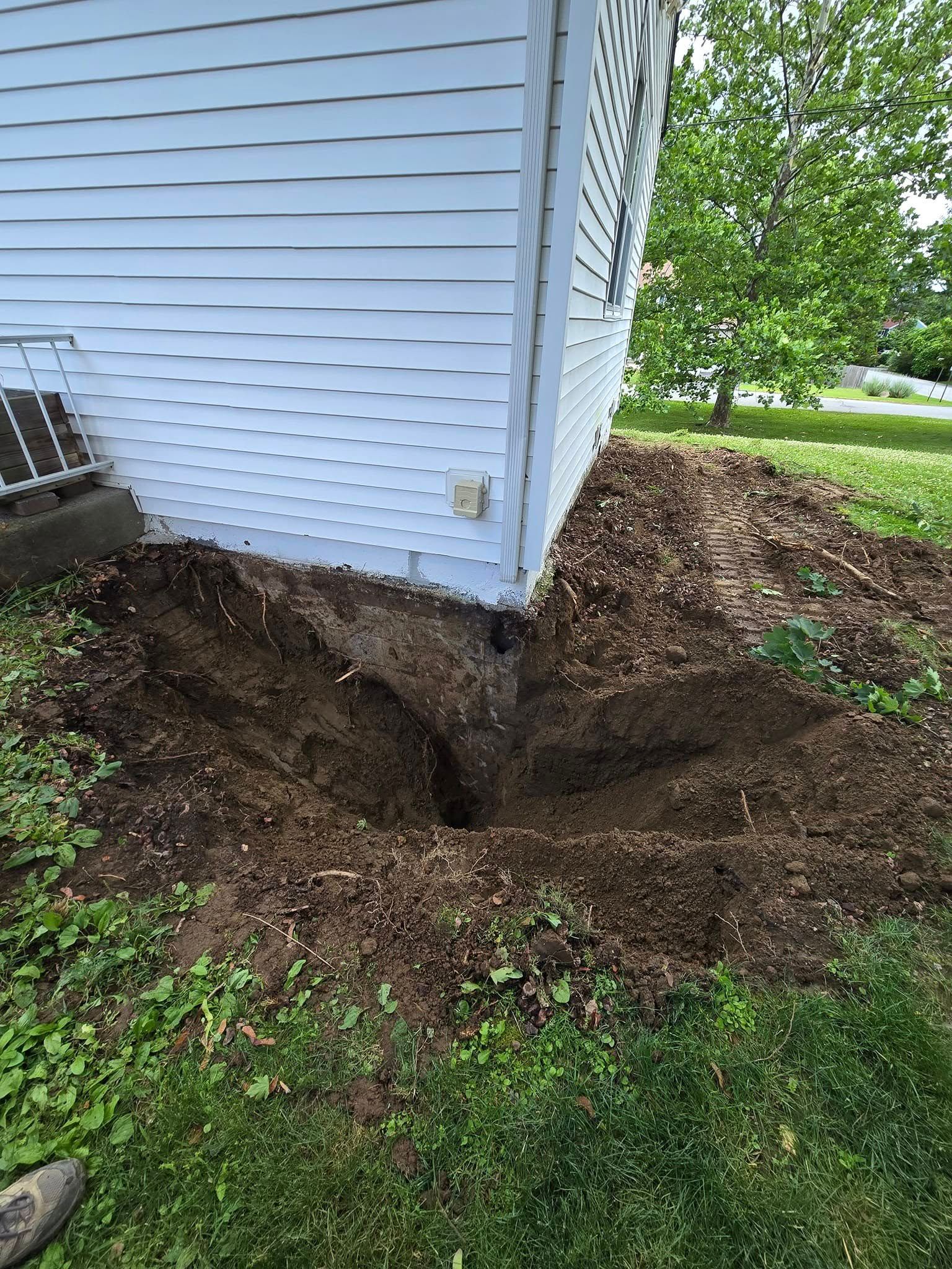 A white house with a hole in the ground in front of it.