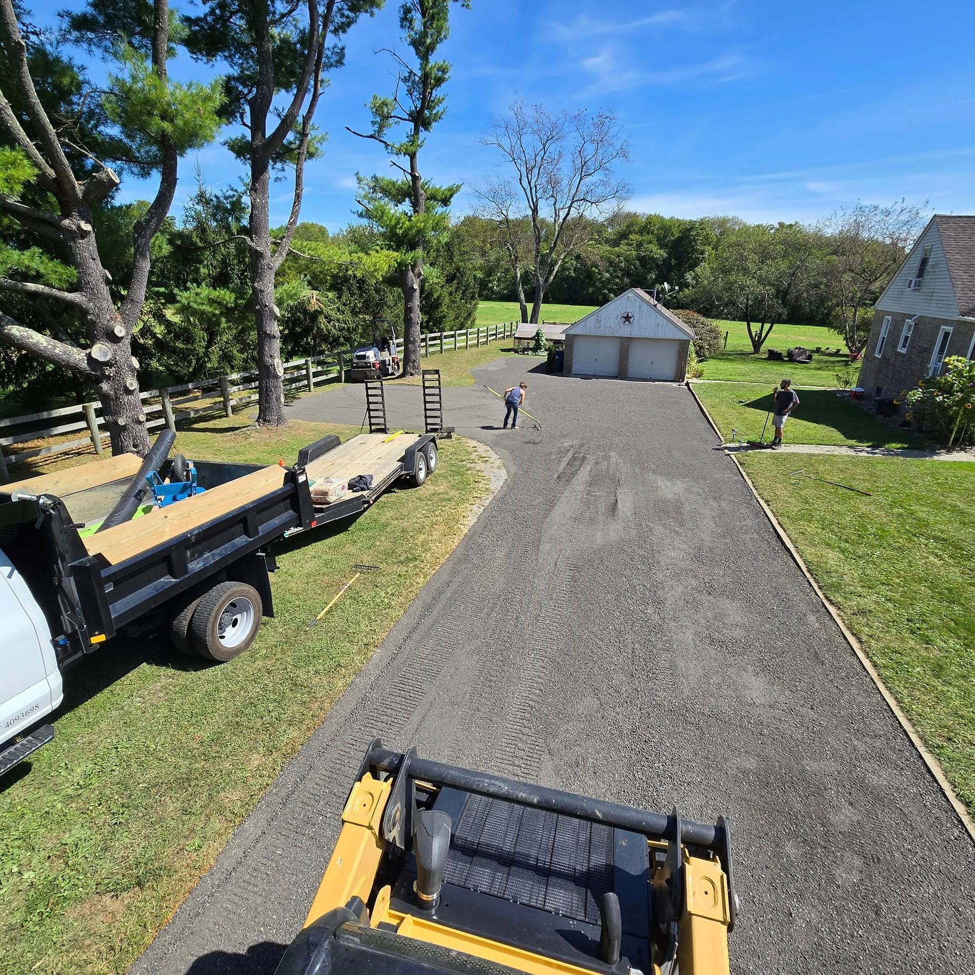 A dump truck is parked on the side of the road next to a trailer.