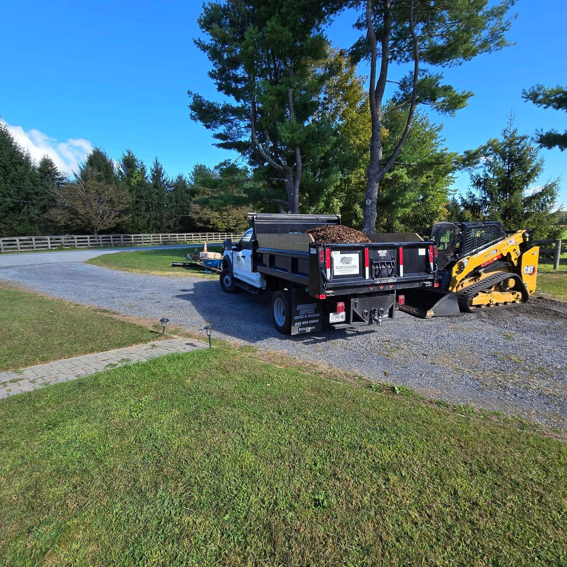 A dump truck is parked next to a bulldozer on a gravel road