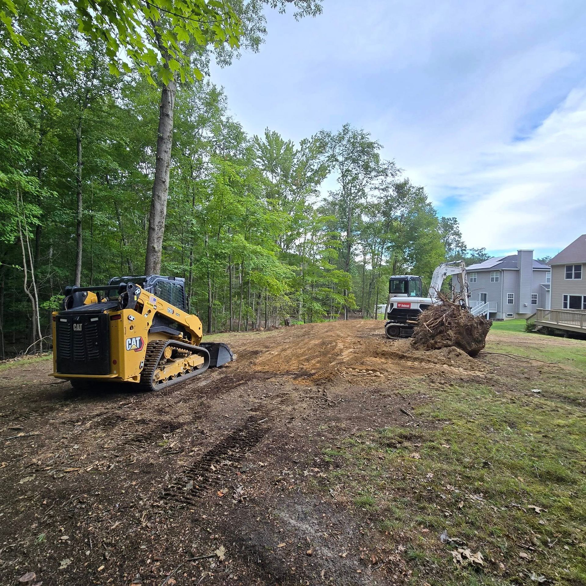 A bulldozer is moving dirt in a yard next to a house.