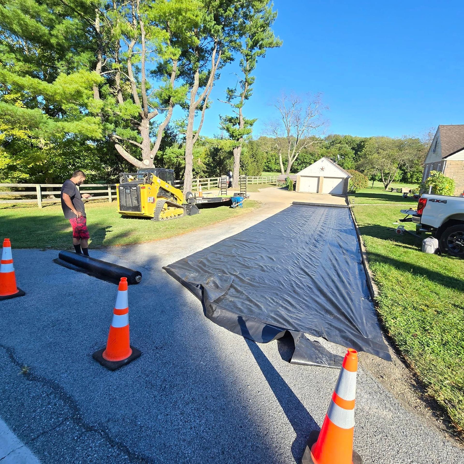 A man is standing next to a black tarp on the side of a road.