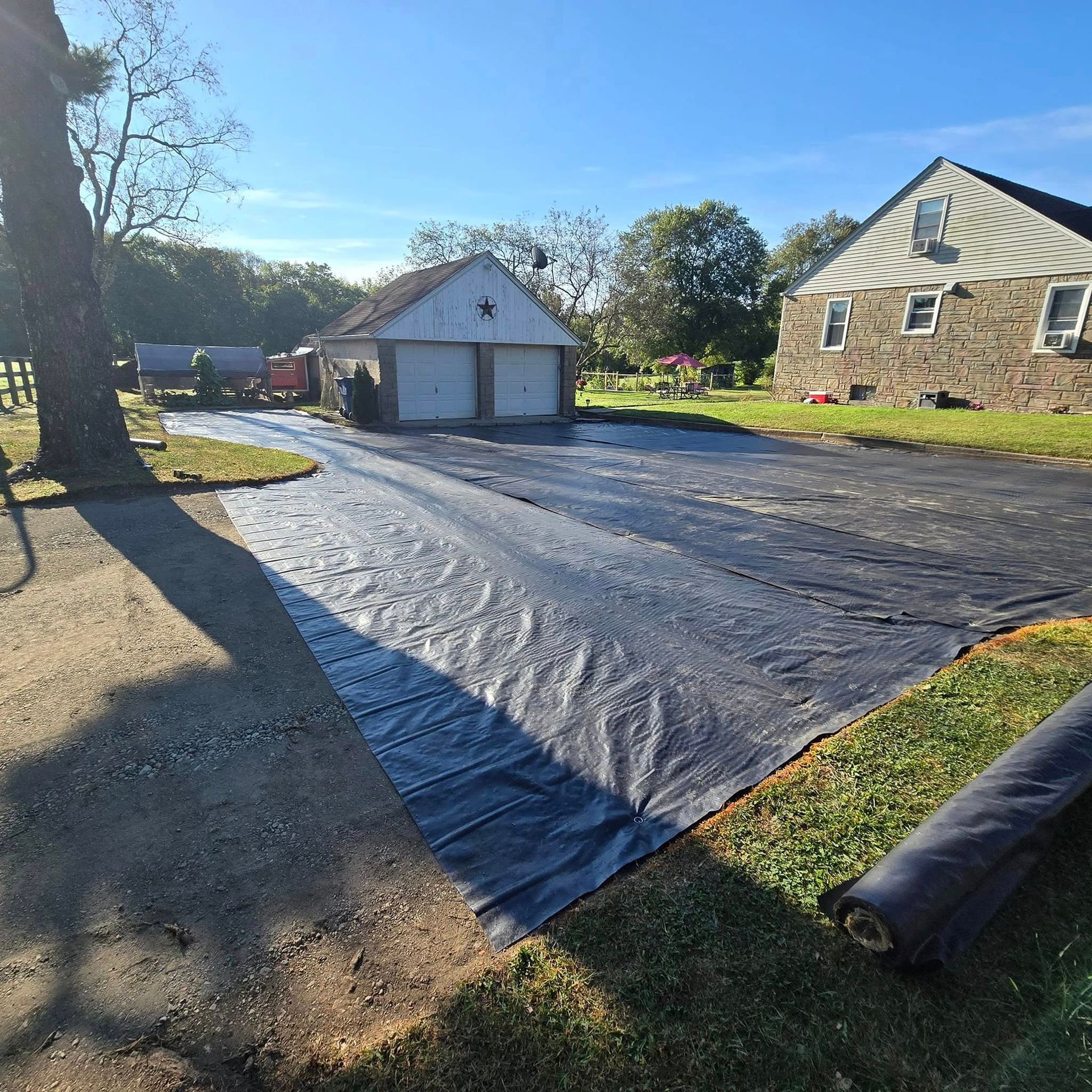 A black tarp is covering a driveway in front of a house.