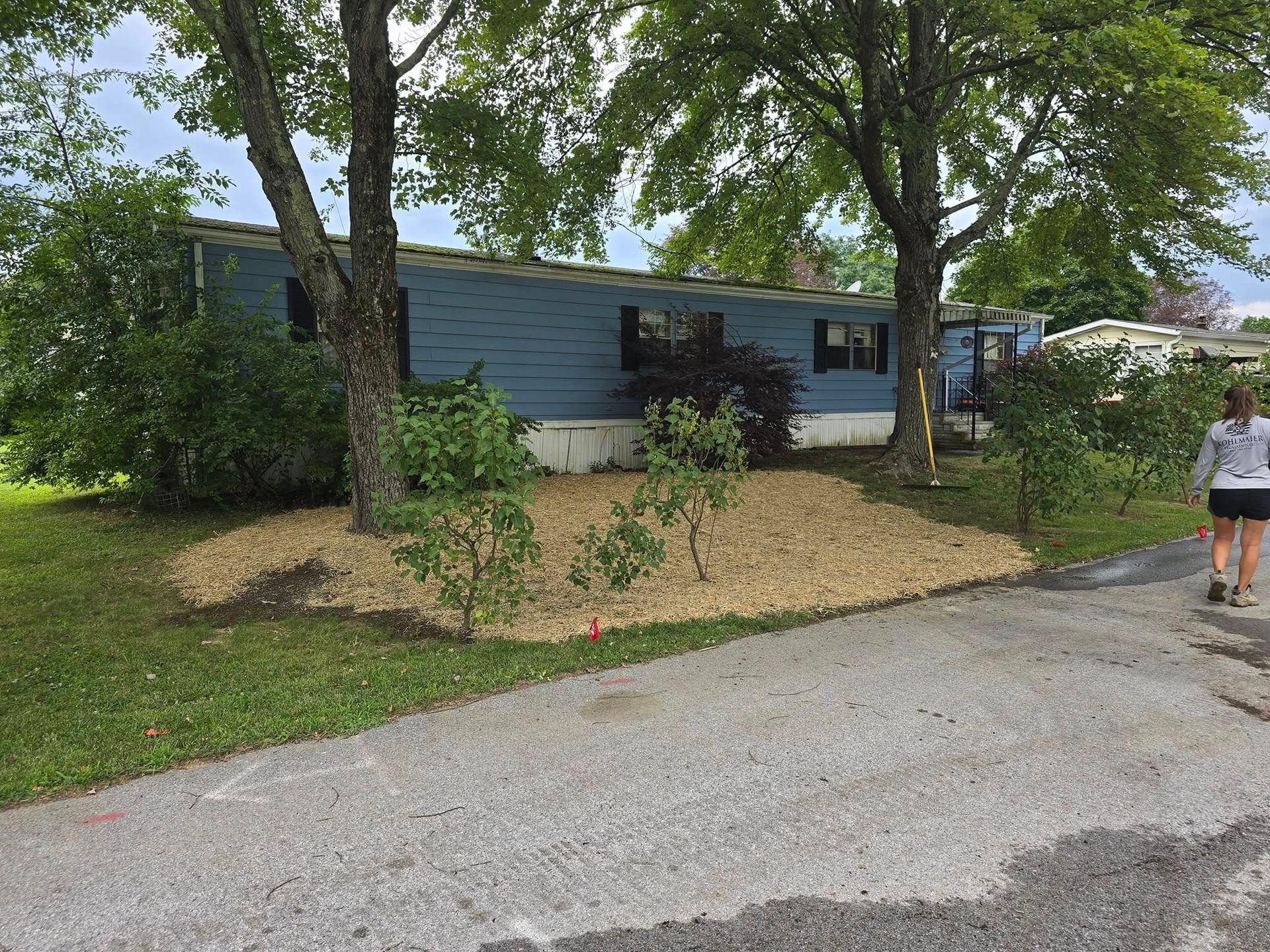 A woman is walking down a road in front of a mobile home.