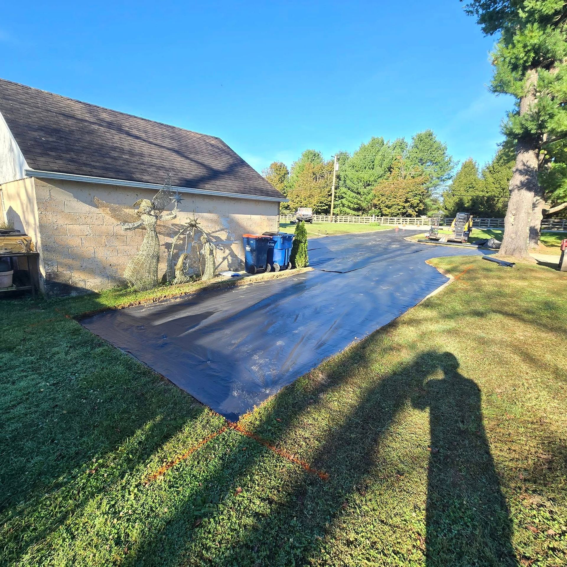 A shadow of a person is cast on the grass in front of a house.
