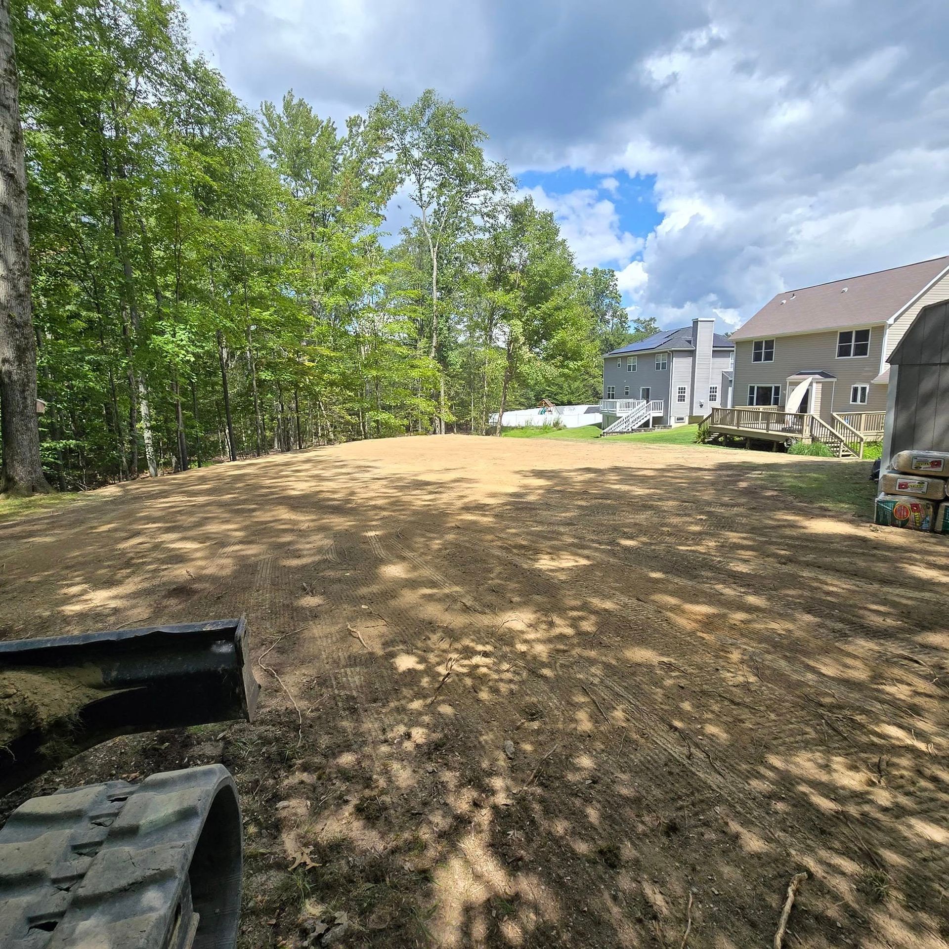 A large dirt field with a house in the background.