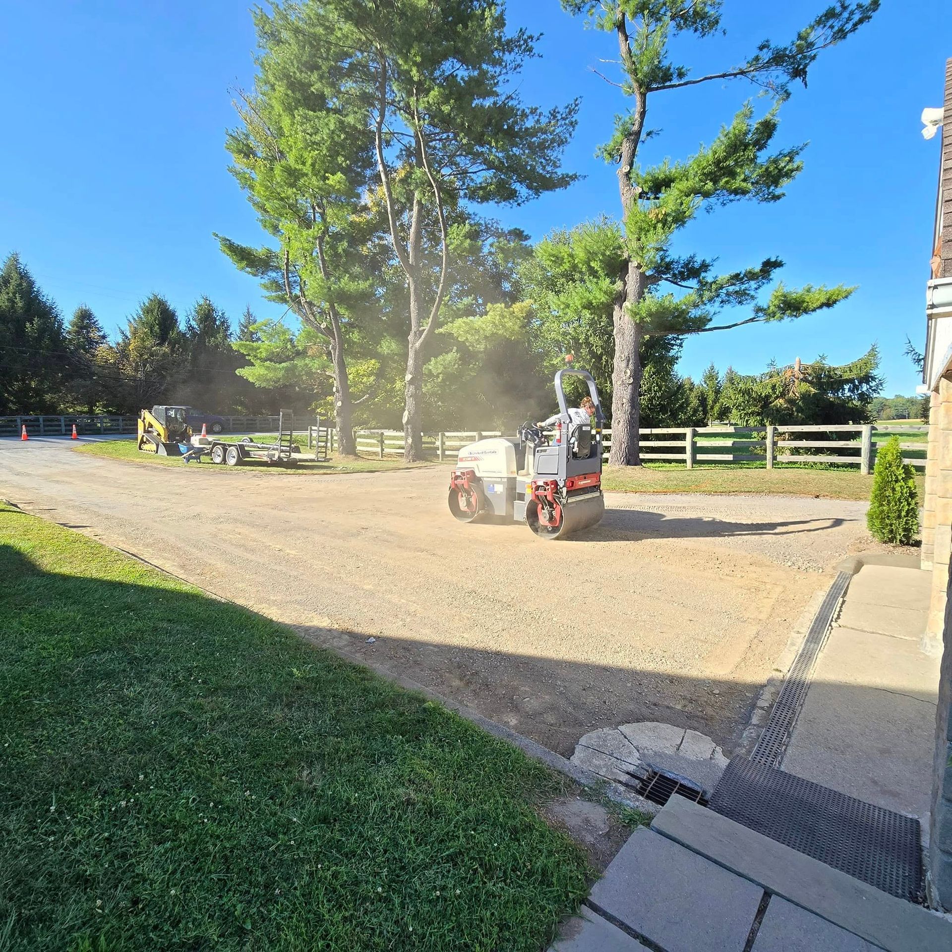 A tractor is driving down a dirt road with trees in the background