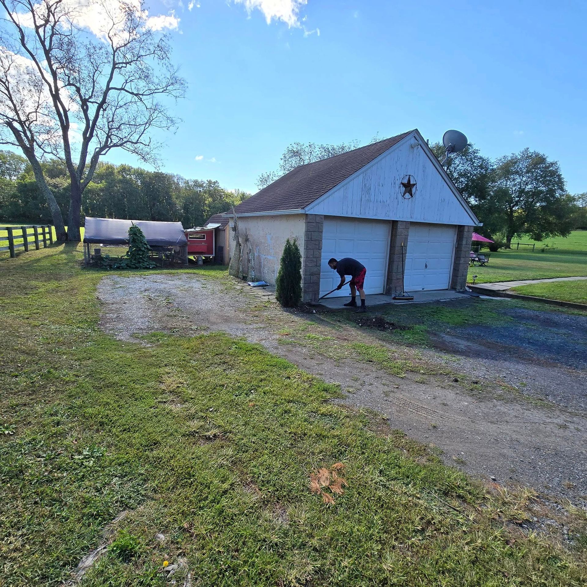 A man is kneeling in front of a garage with a cross on it.
