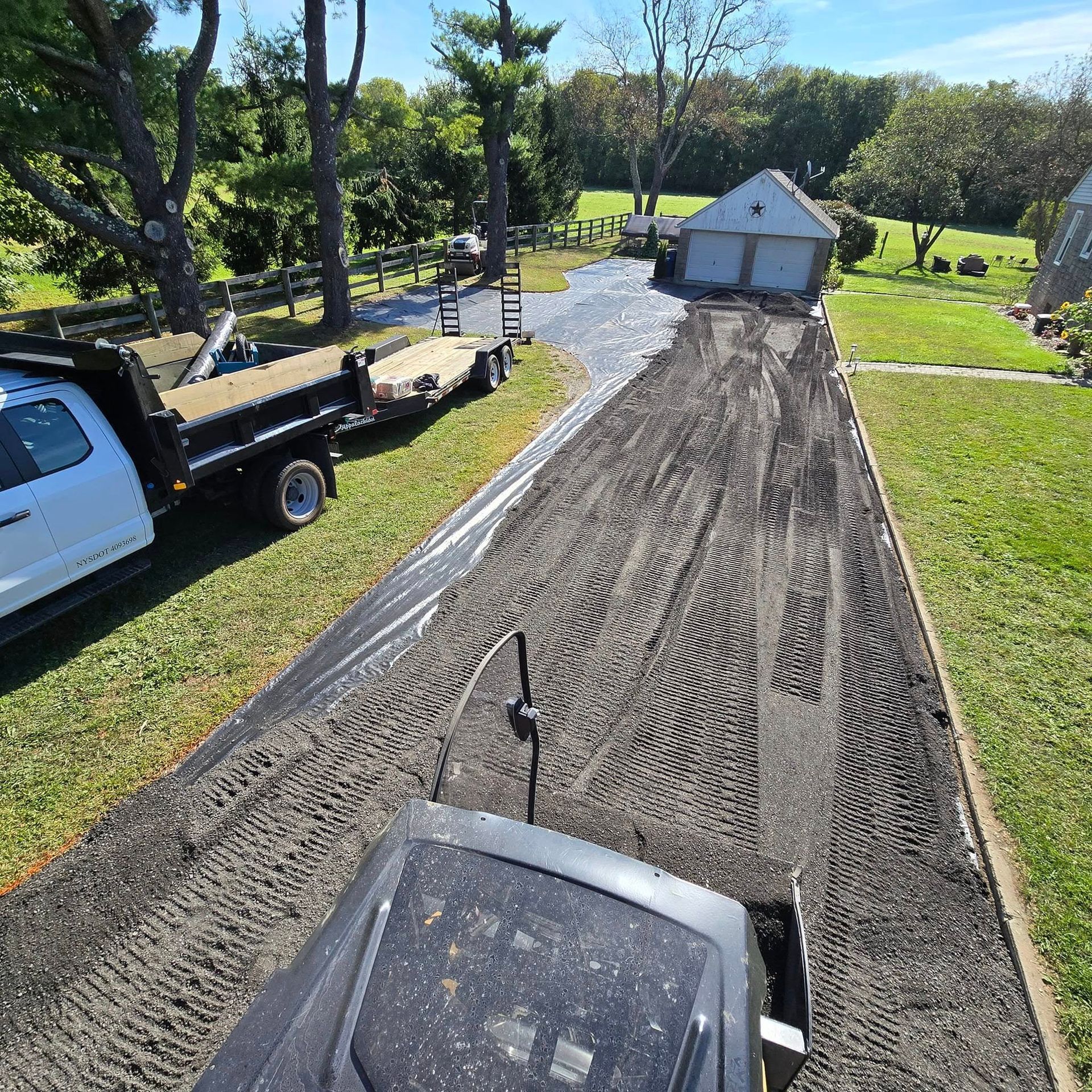 A dump truck is parked on the side of a dirt road.