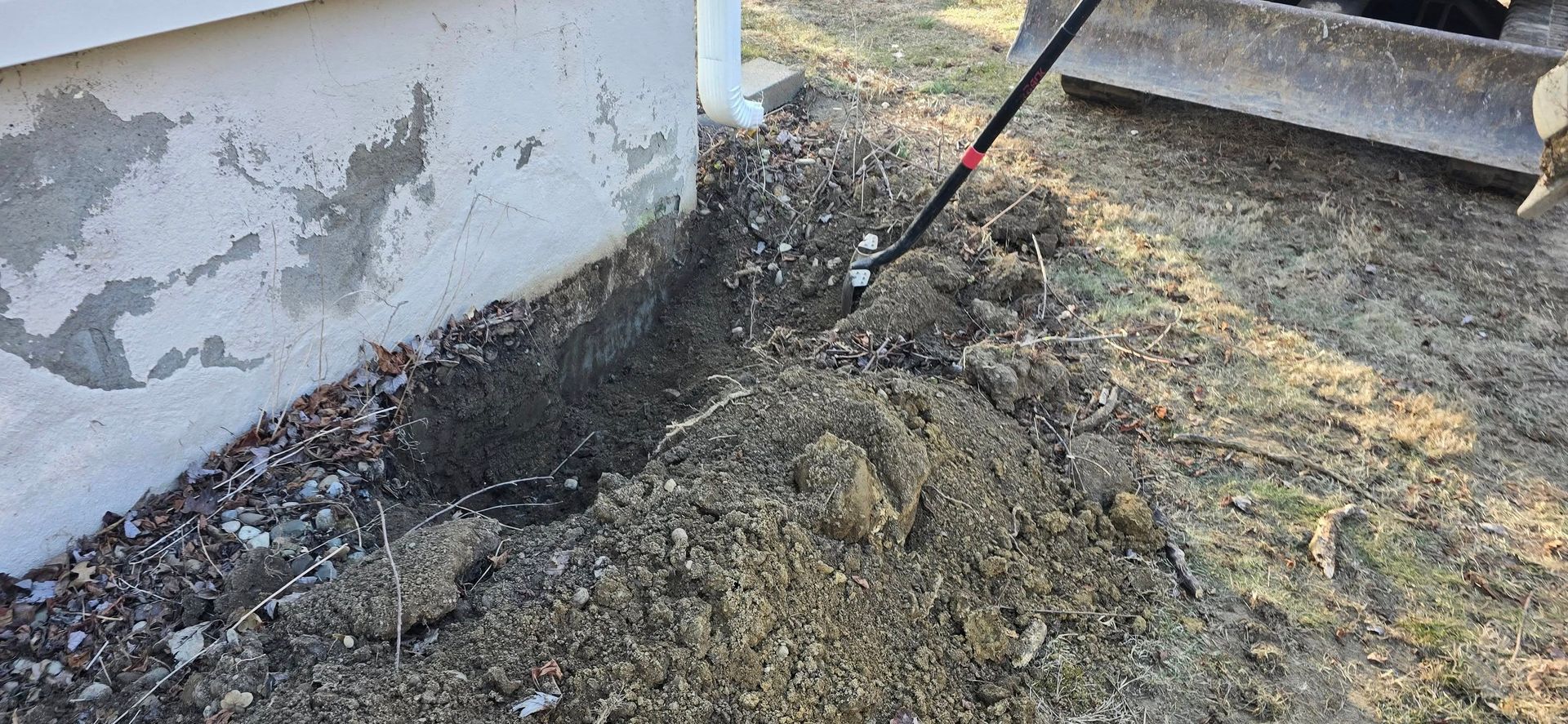 A person is digging a hole in the ground next to a house.