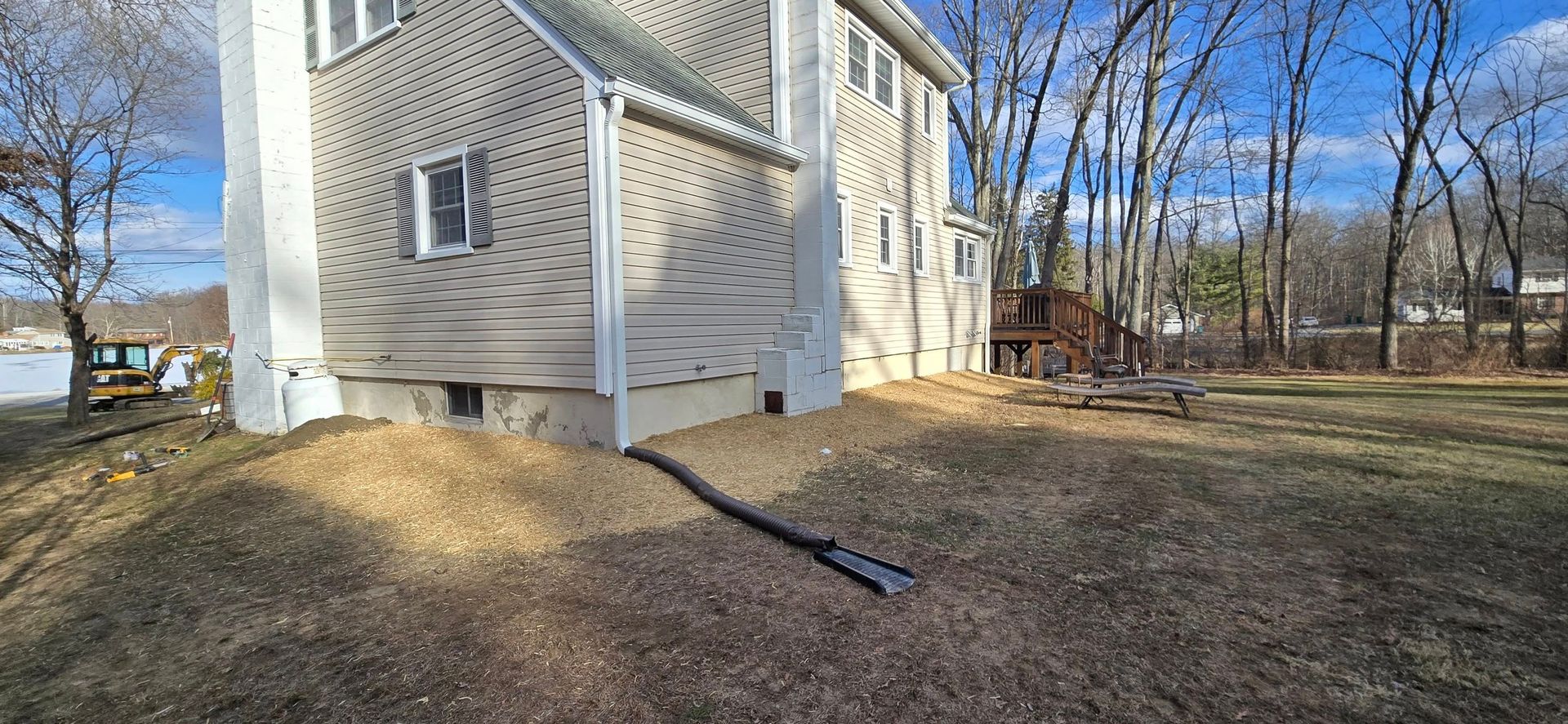 The backyard of a house with a lot of grass and trees in the background.
