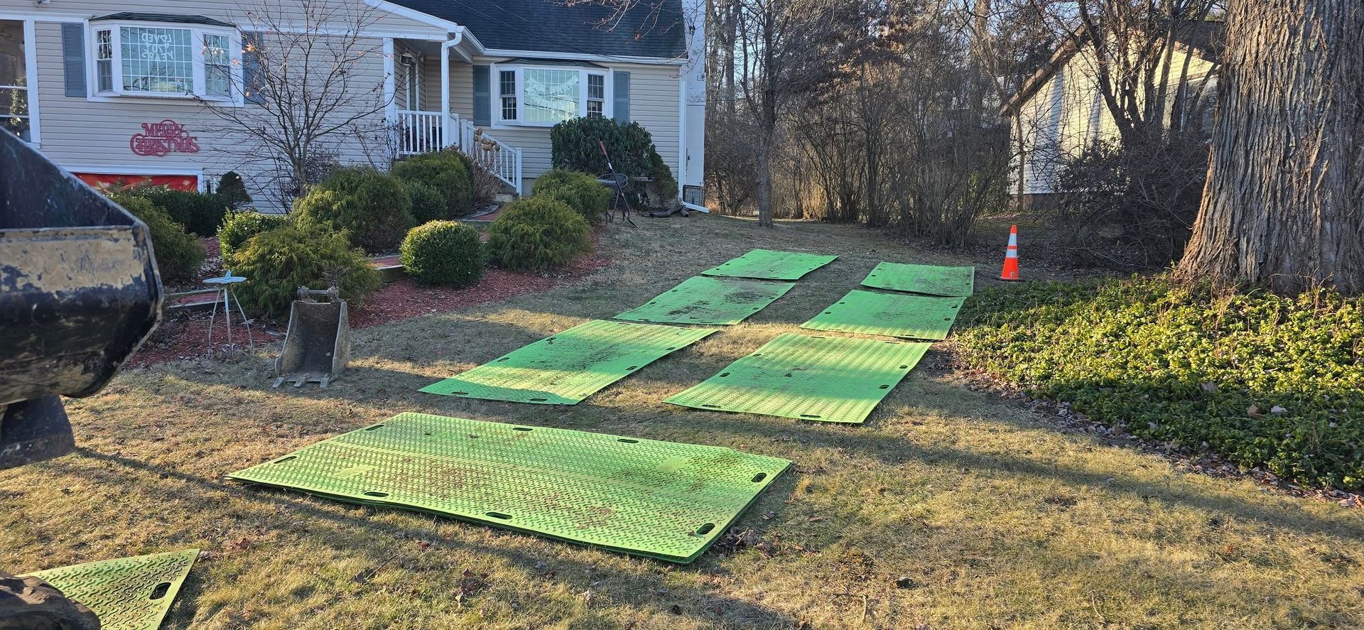A bunch of green plates are sitting in the grass in front of a house.
