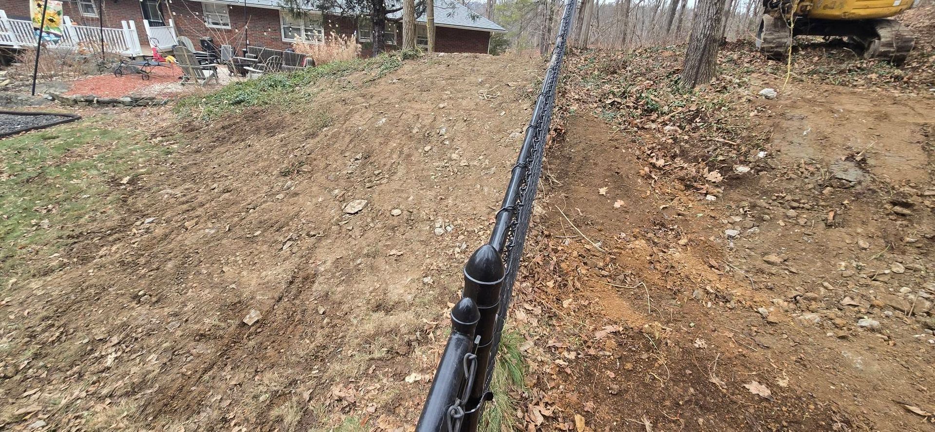 A chain link fence is being built in a dirt field.