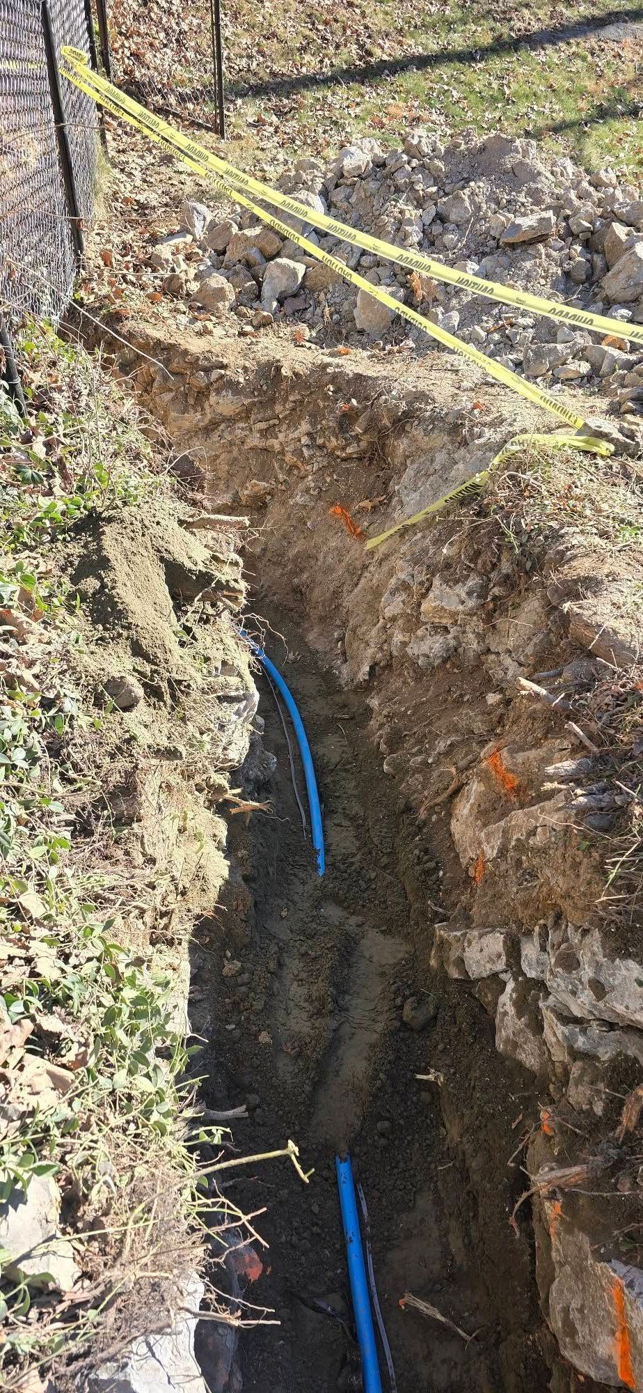 A blue pipe is being installed in a hole in the ground.