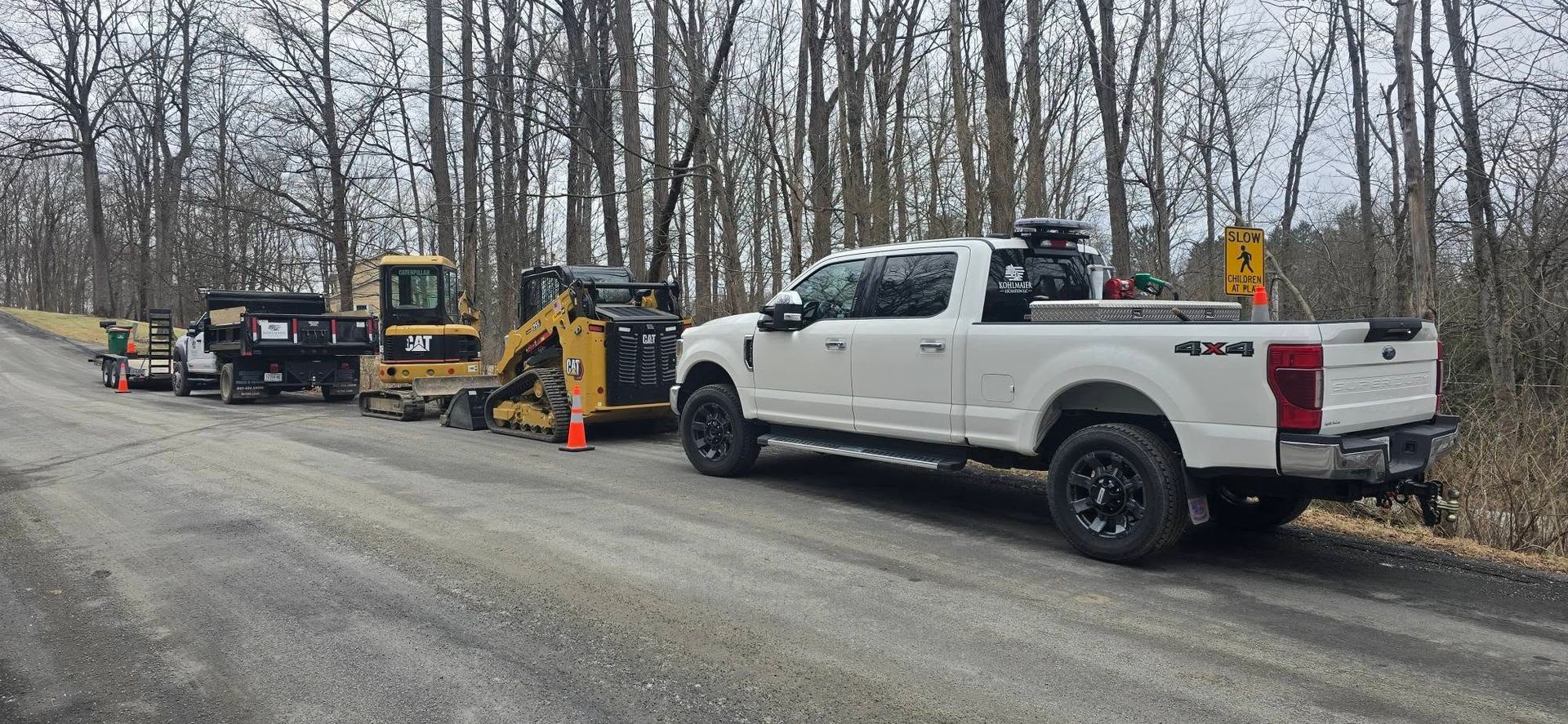 A white truck is parked on the side of a road next to a bulldozer.