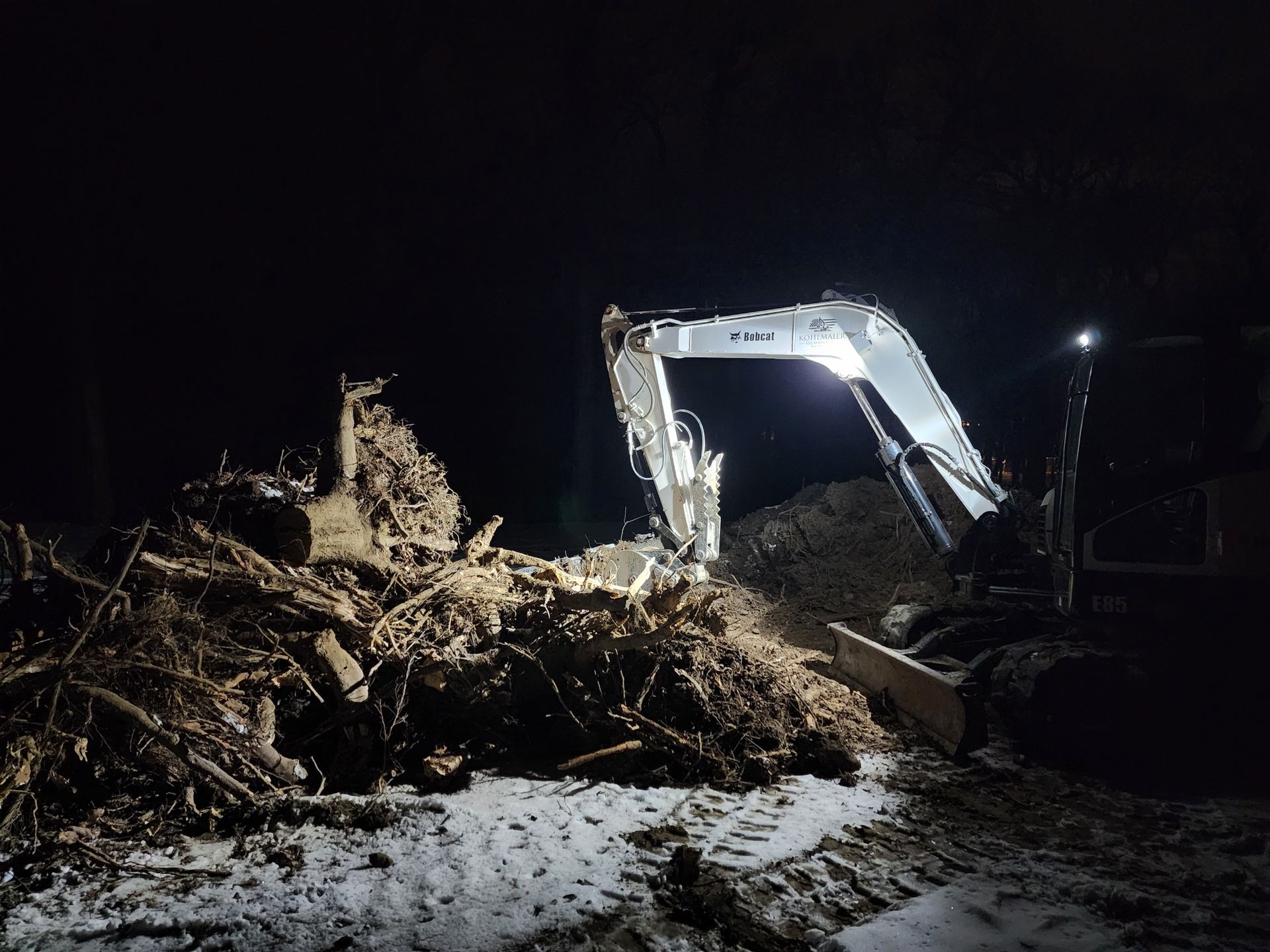 A bulldozer is digging a hole in the dirt at night.