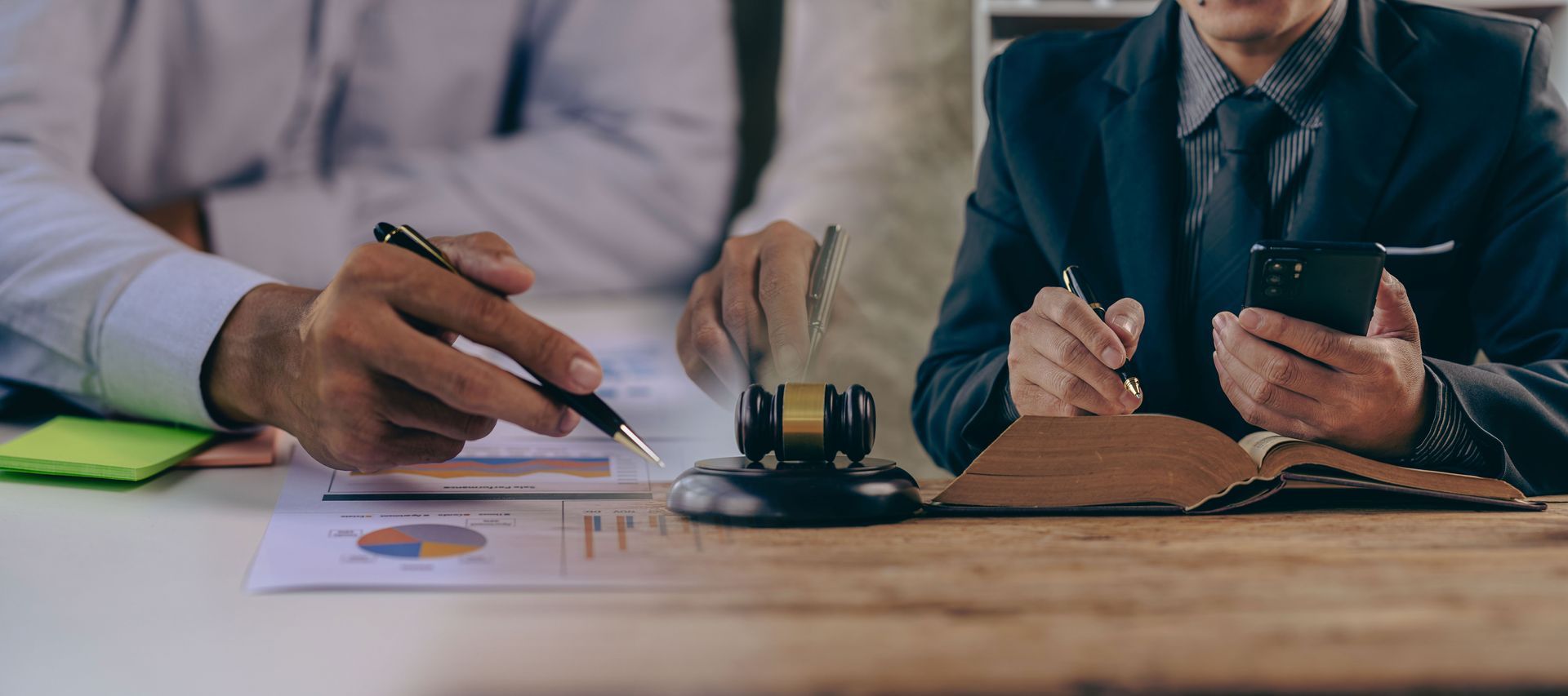 Two men are sitting at a table with a judge 's gavel and a cell phone.
